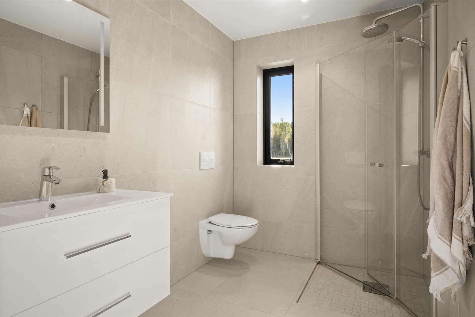 Stilrent og lekkert bad med flislagte vegger og gulv.
Badet i boligens første etasje ligger praktisk til med adkomst direkte fra gangen. Galleribilde