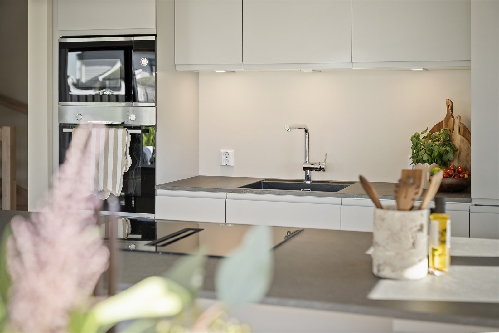 Stilrent kjøkken med slette fronter og benkeplate i mørk laminat med steinimitert overflate. Galleribilde