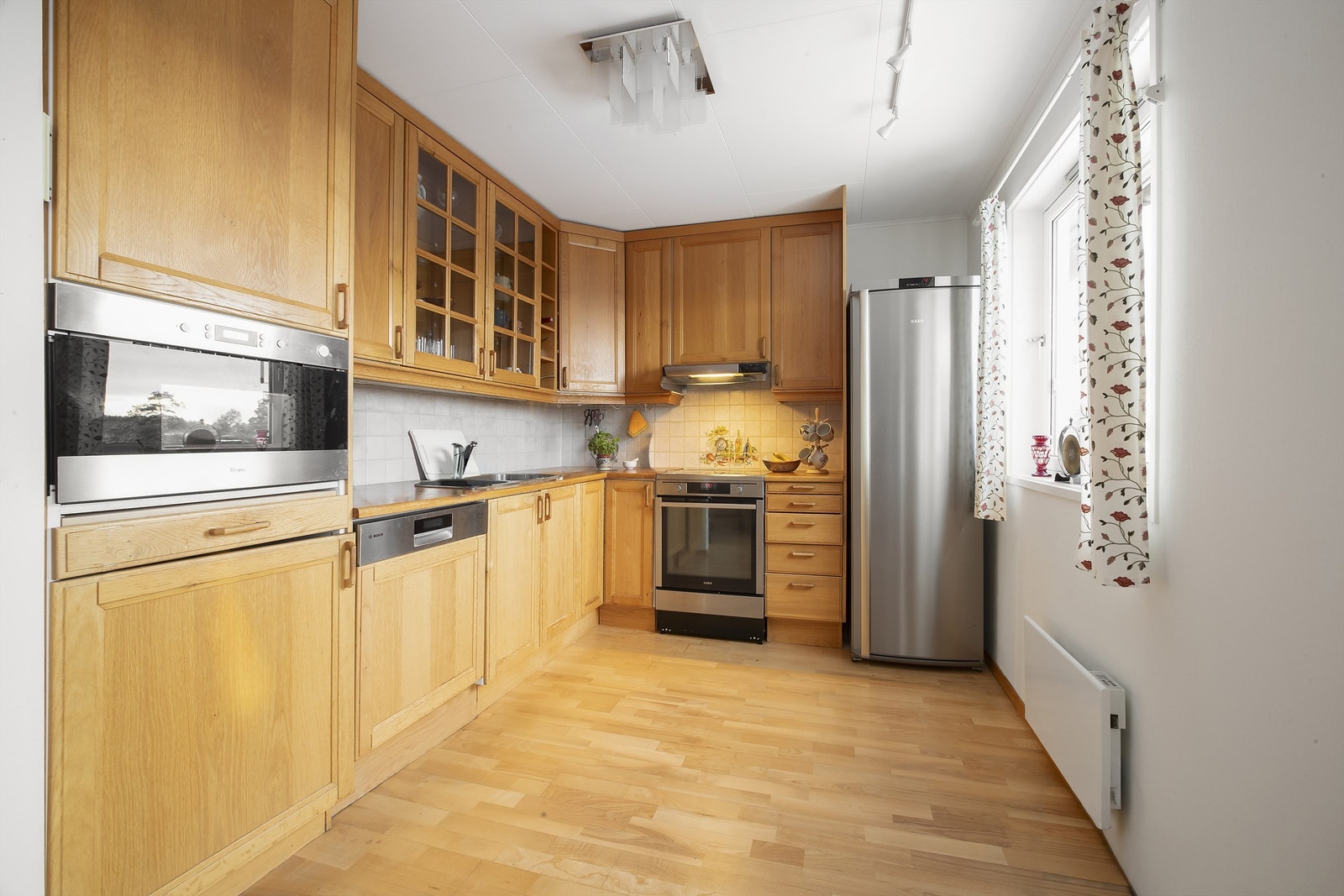 Kjøkkeninnredning fra Norema med fronter i heltre eik og fliser på vegg over benkeplate Galleribilde