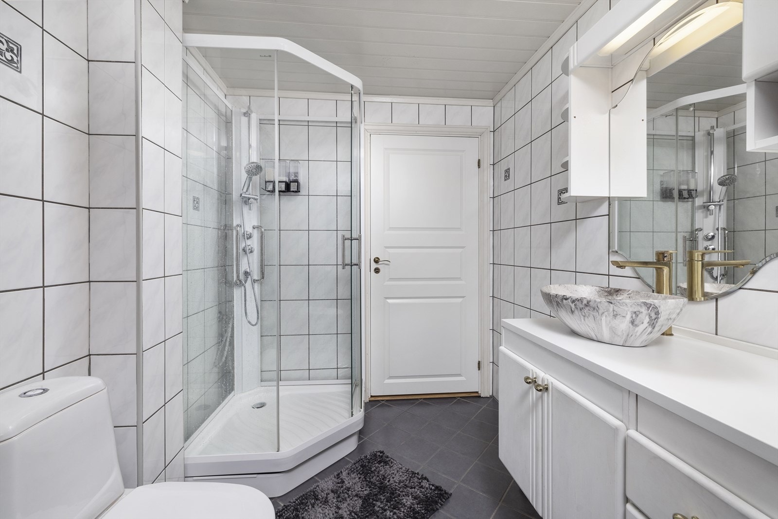 Vaskerom/bad fra 90 tallet. Våtrommet har fliser på gulv og vegger. Himling med malte panelplater. Dusjkabinettet som er avbildet er demontert og fjernet. Galleribilde