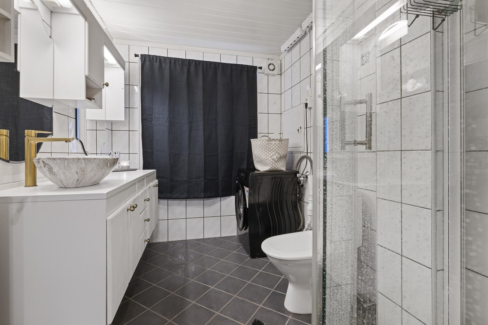 Innredning med frittstående servant og toalett. Dusjkabinettet som er avbildet er demontert og fjernet. Rommet har opplegg for vaskemaskin. Galleribilde