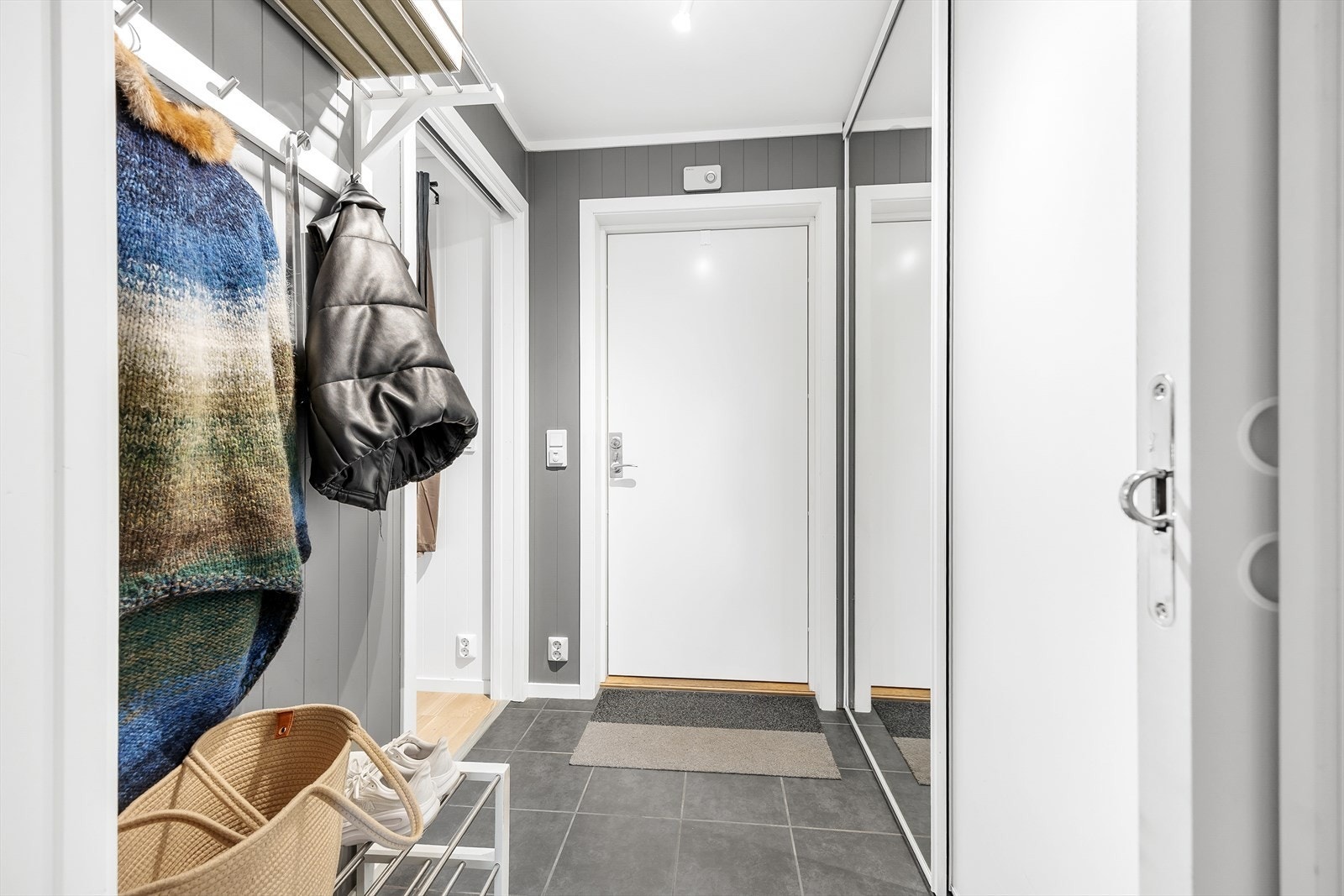 Entréen gir et godt førsteinntrykk av leiligheten med pene overflater i en grå fargepalett, og med lun gulvvarme under det flislagte gulvet. Galleribilde
