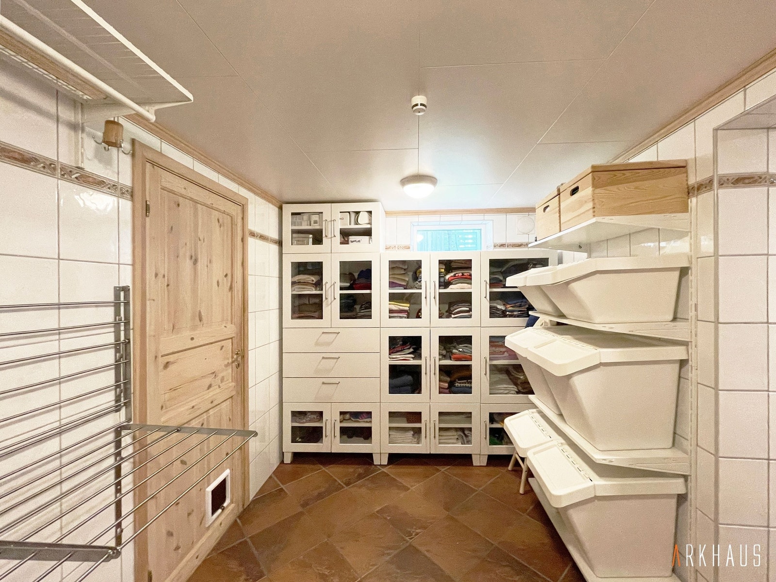 Stort vaskerom med veggmontert tørkestativ, innebygde skap og kurver på veggmonterte hyller Galleribilde