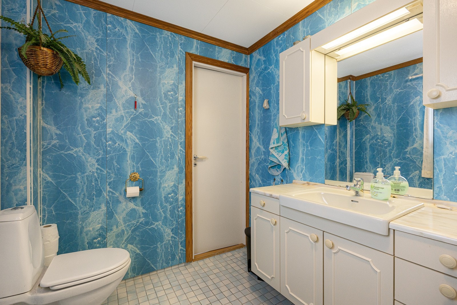 Badet er innredet med våtromsplater på veggene og mosaikkfliser på gulvet. Varmekabler er installert, og badet har toalett og badekar med dusjløsning. Galleribilde