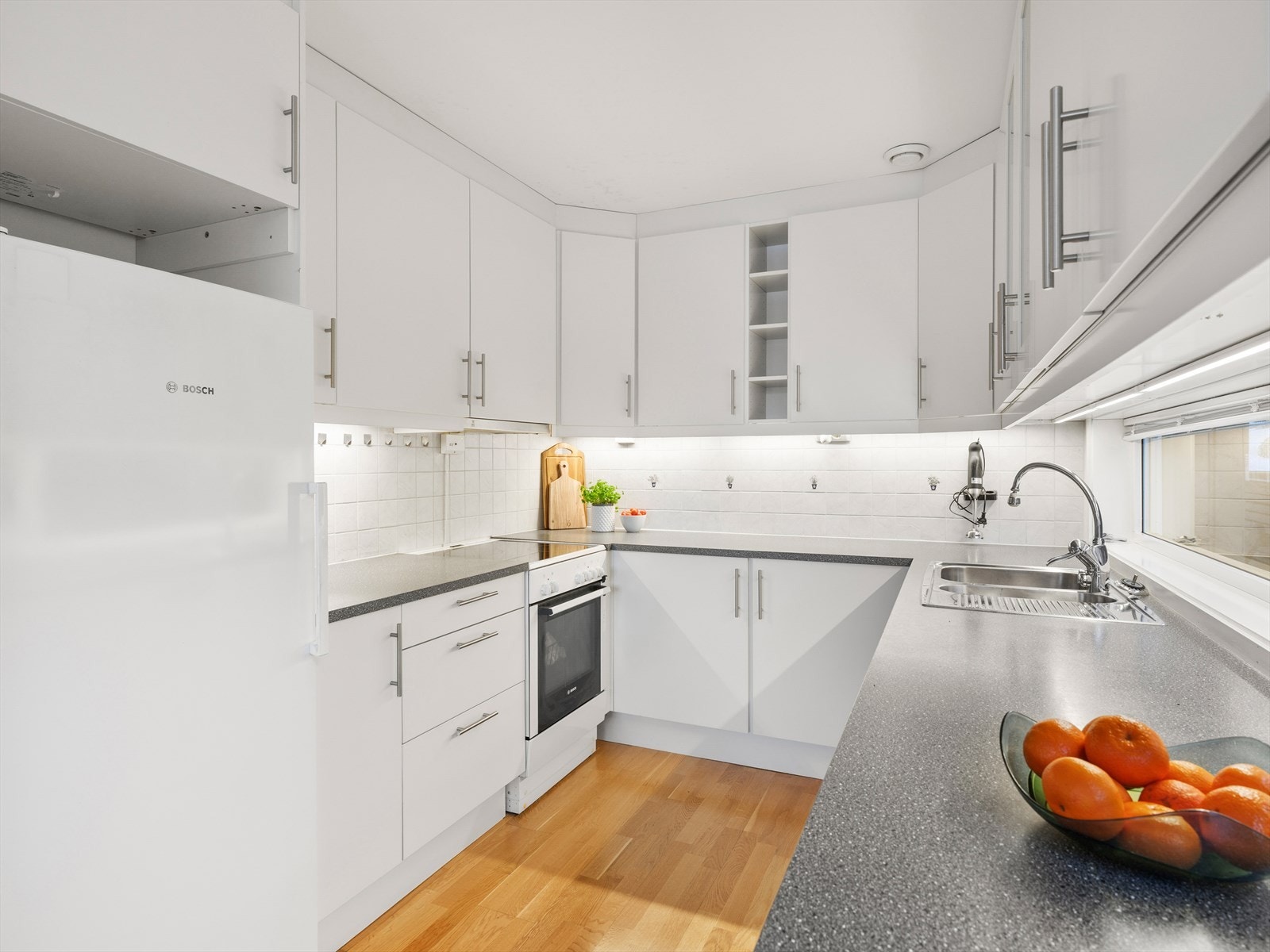 Benkeplate med god arbeidsflate. Fliser og belysning over benk. Galleribilde