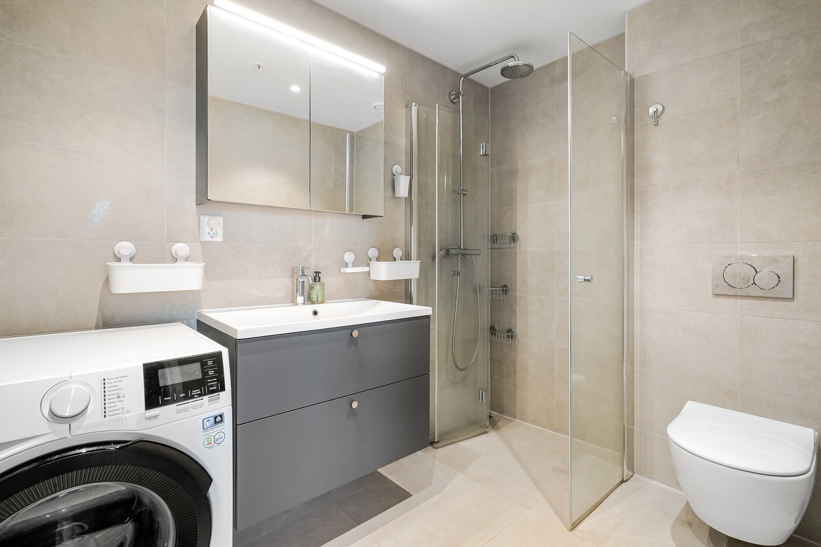 Moderne, flislagt bad med elektrisk gulvvarme, regndusj og opplegg for vaskesøyle. Galleribilde