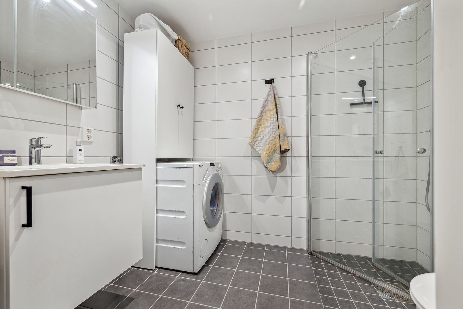 Lekkert og moderne bad med dusjhjørne og opplegg for vaskemaskin. Galleribilde