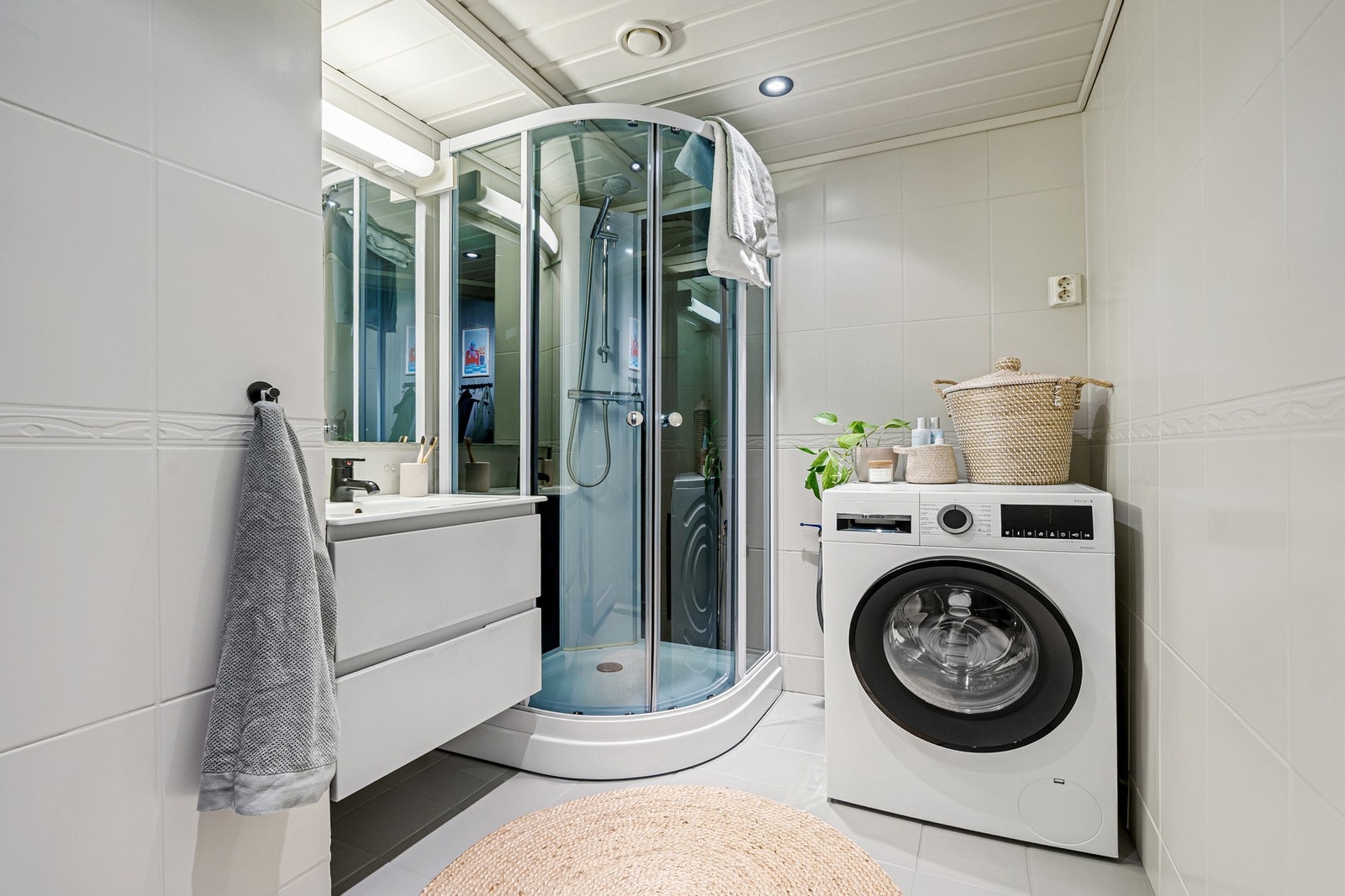 Badet har en effektiv planløsning med dusjkabinett og plass til vaskemaskin, samt god belysning som gir et lyst og ryddig inntrykk. Galleribilde