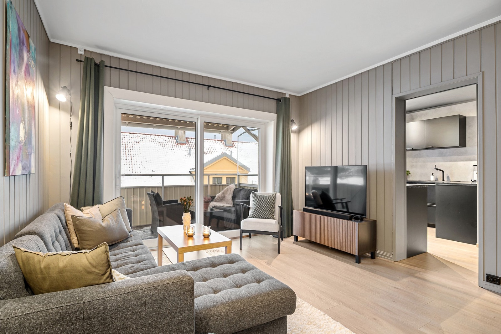 Stue med delvis åpen løsning mot kjøkkenet. Overgangen gir en god balanse mellom åpenhet og avskjerming, og bidrar til en funksjonell romfølelse. Galleribilde