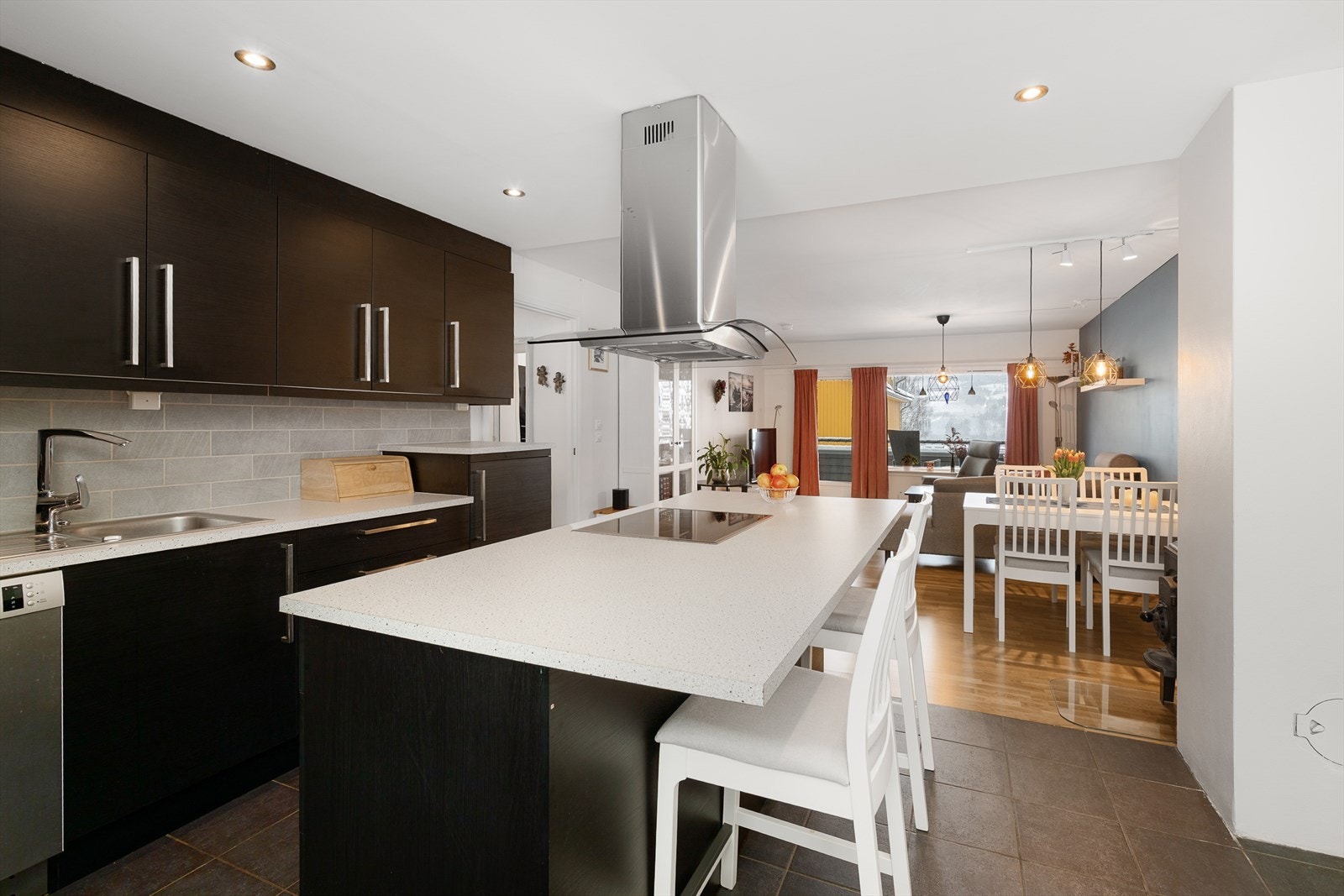 En stor kjøkkenøy med integrert komfyr fungerer som et naturlig samlingspunkt i rommet. Galleribilde