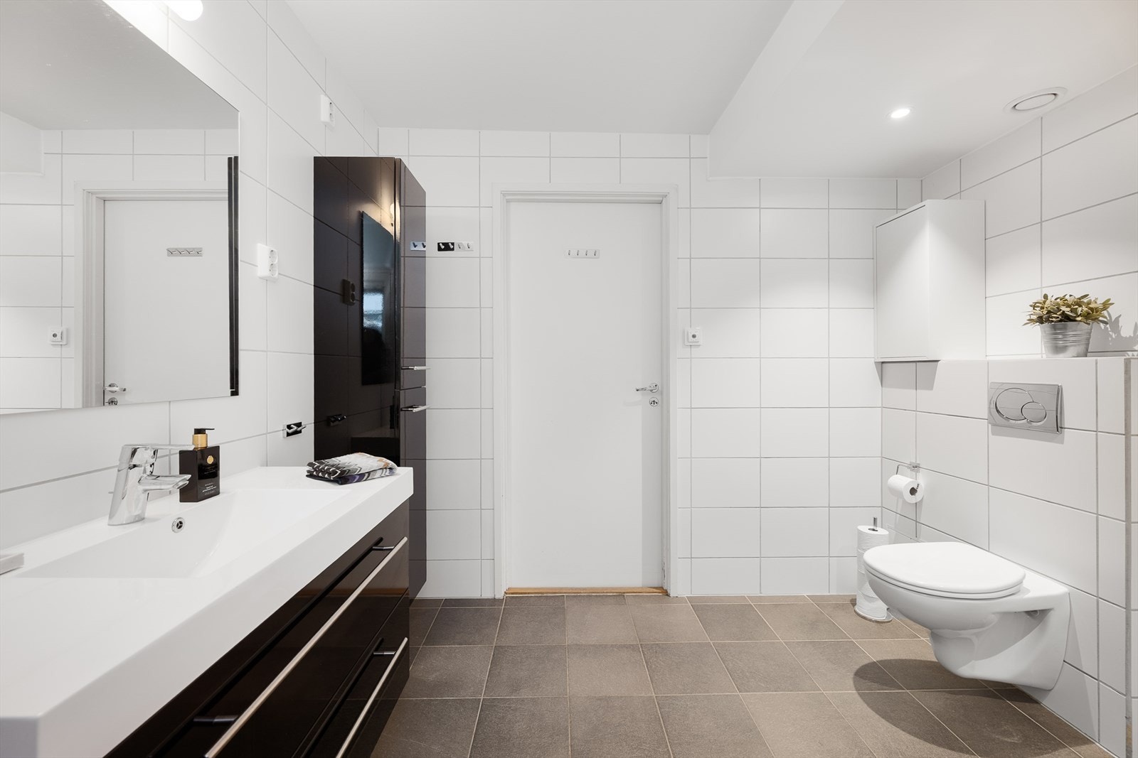 Rommet er utstyrt med vegghengt toalett og baderomsinnredning med sorte, glatte fronter. Galleribilde