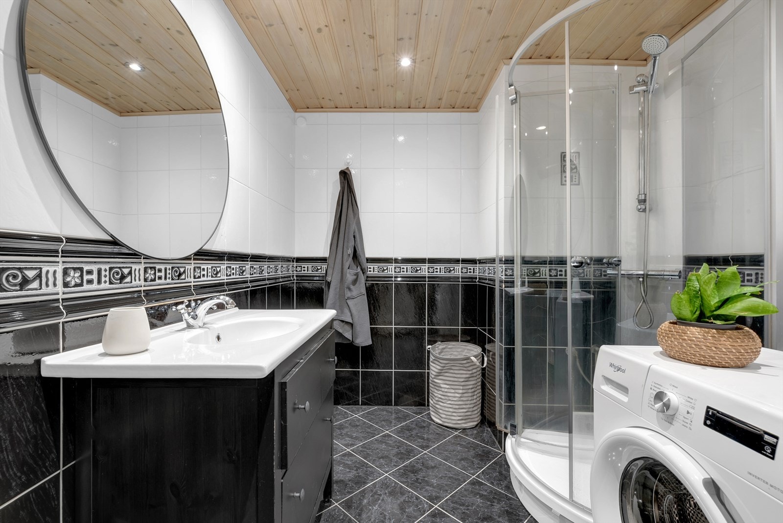 Romslig, flislagt bad med dusjkabinett, servantinnredning og opplegg for vaskemaskin. Galleribilde