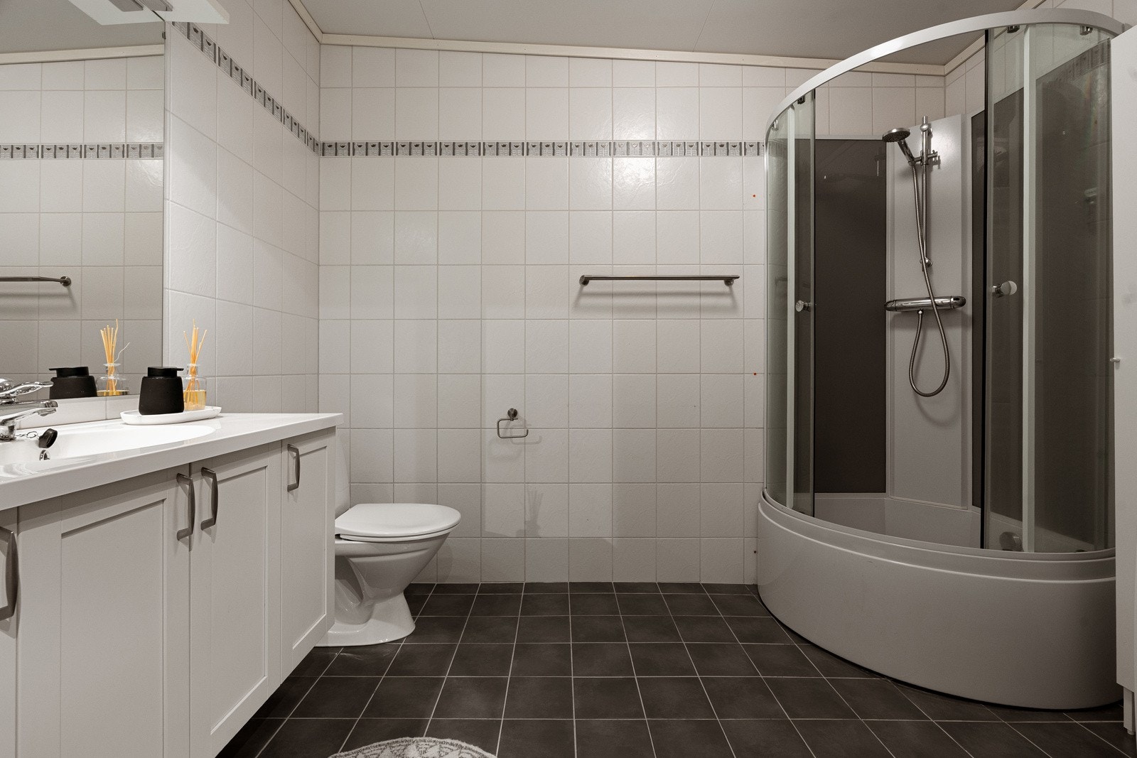 Badet er innredet med dusjkabinett, gulvmontert toalett samt opplegg for vaskemaskin/tørketrommel. Galleribilde