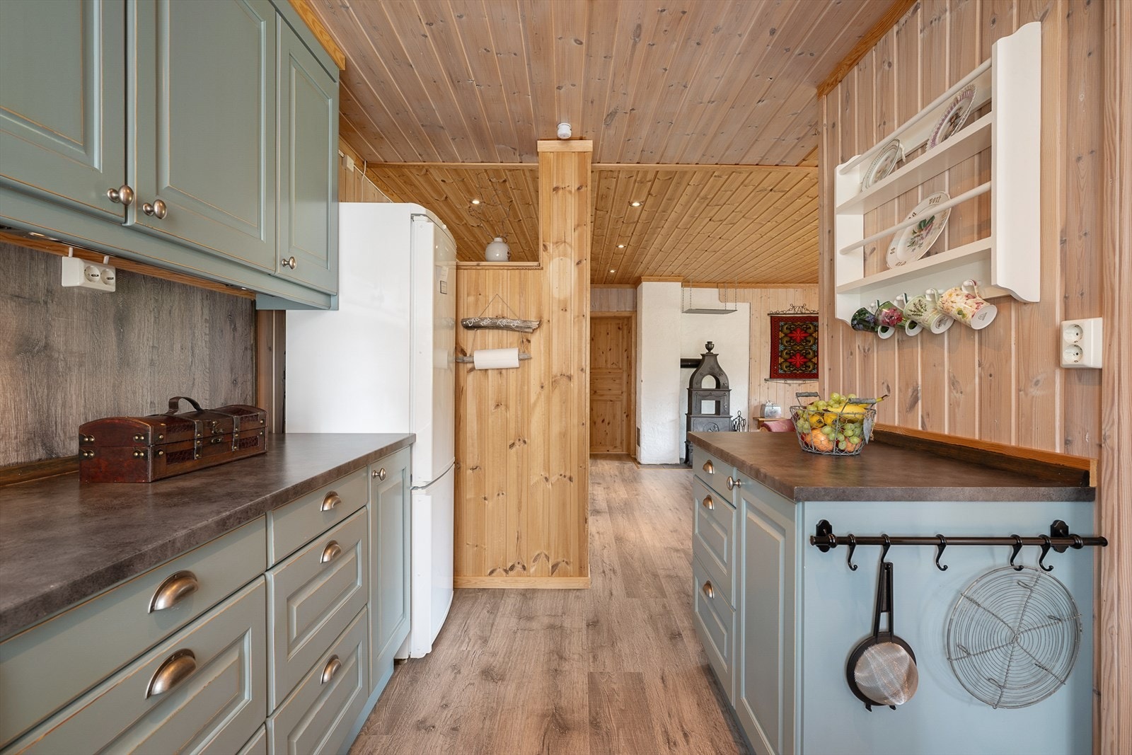 Kjøkkenet er malt i en lun og delikat grønnfarge som er en fin kontrast til de trehvite veggene. Galleribilde