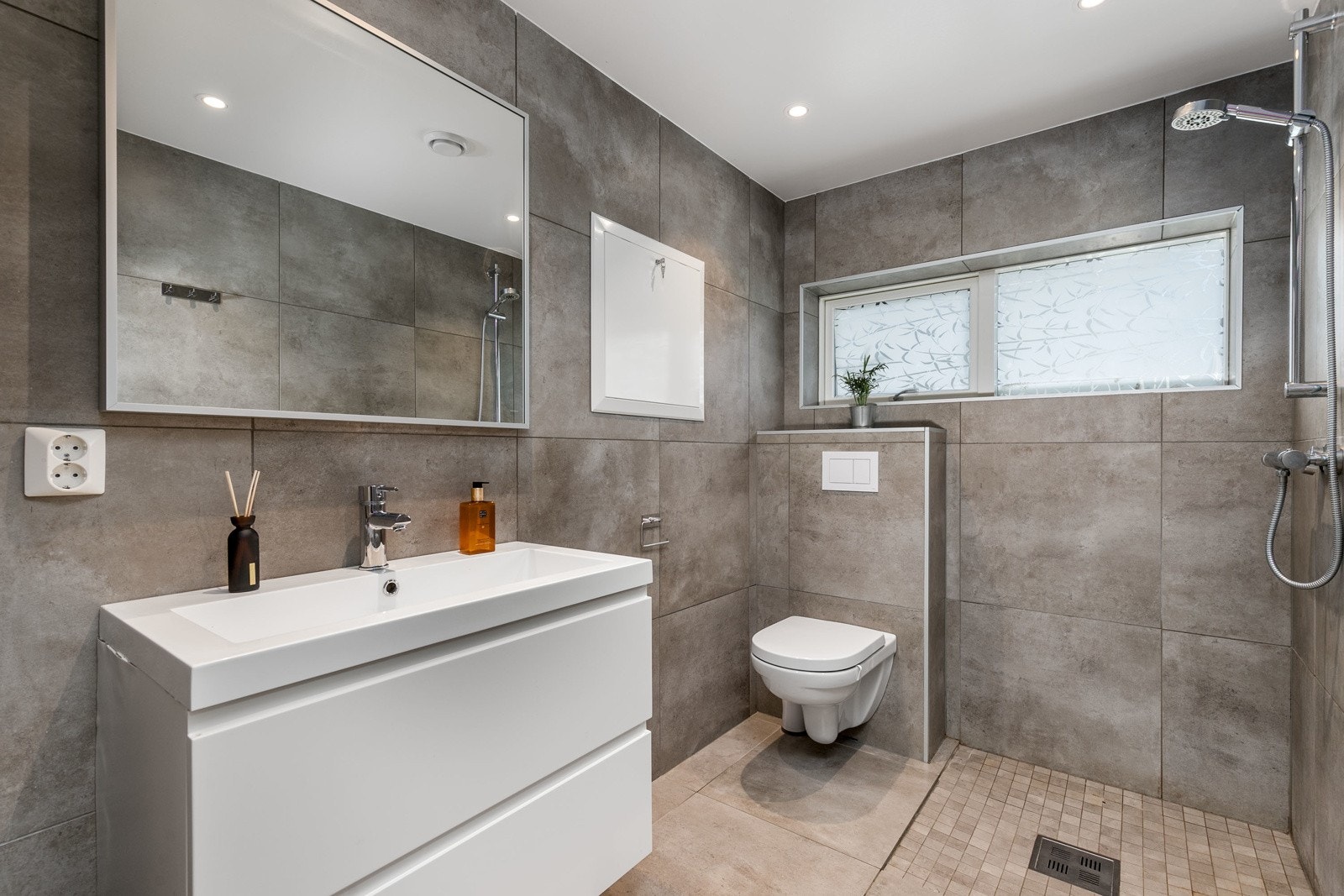 Delikat bad i 1. etg med fliser på gulv med gulvvarme og flislagte overflater. Galleribilde