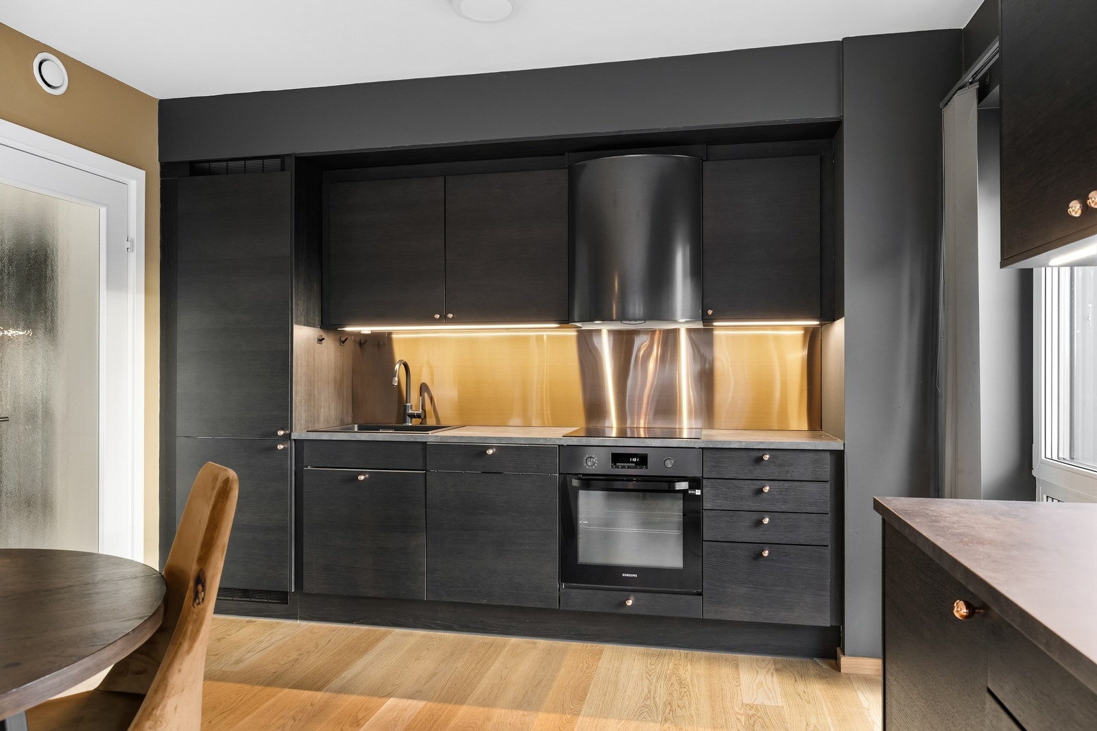 Kjøkkenet er utstyrt med nedfelt platetopp, integrert komfyr og ventilator. Galleribilde