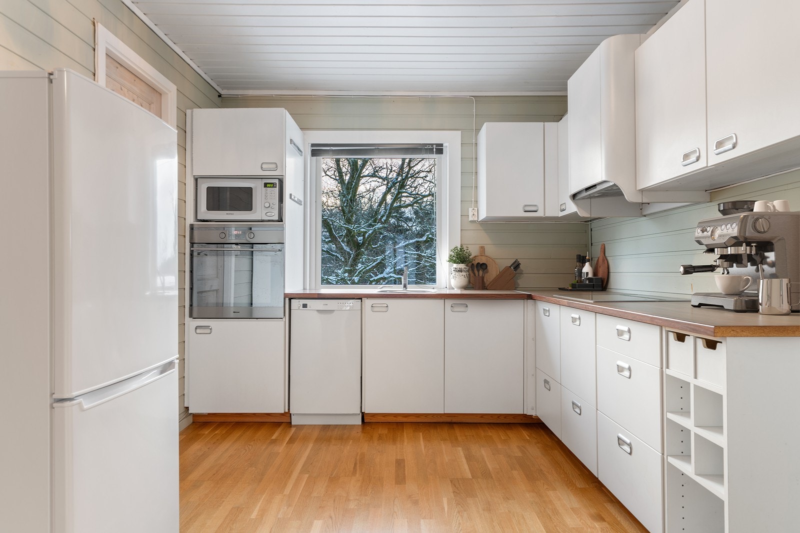 Lyst og pent kjøkken med integrert koketopp og stekeovn Galleribilde