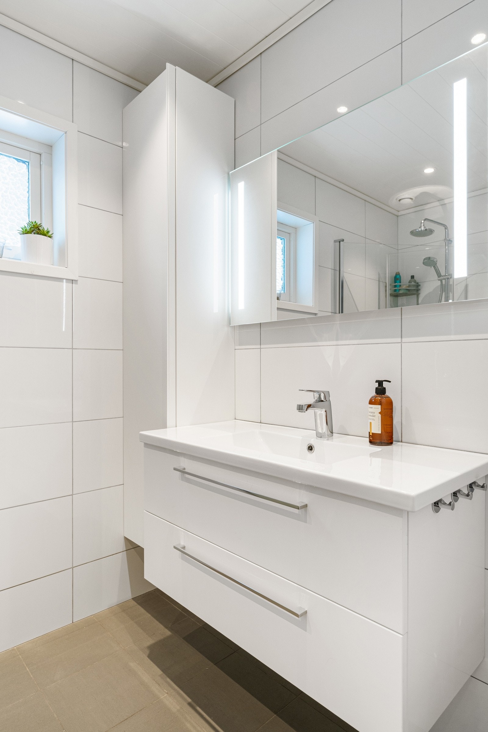 Rommet er ellers utstyrt med servantskap,vegghengt høyskap og speil med innfelte lysdetaljer. Galleribilde