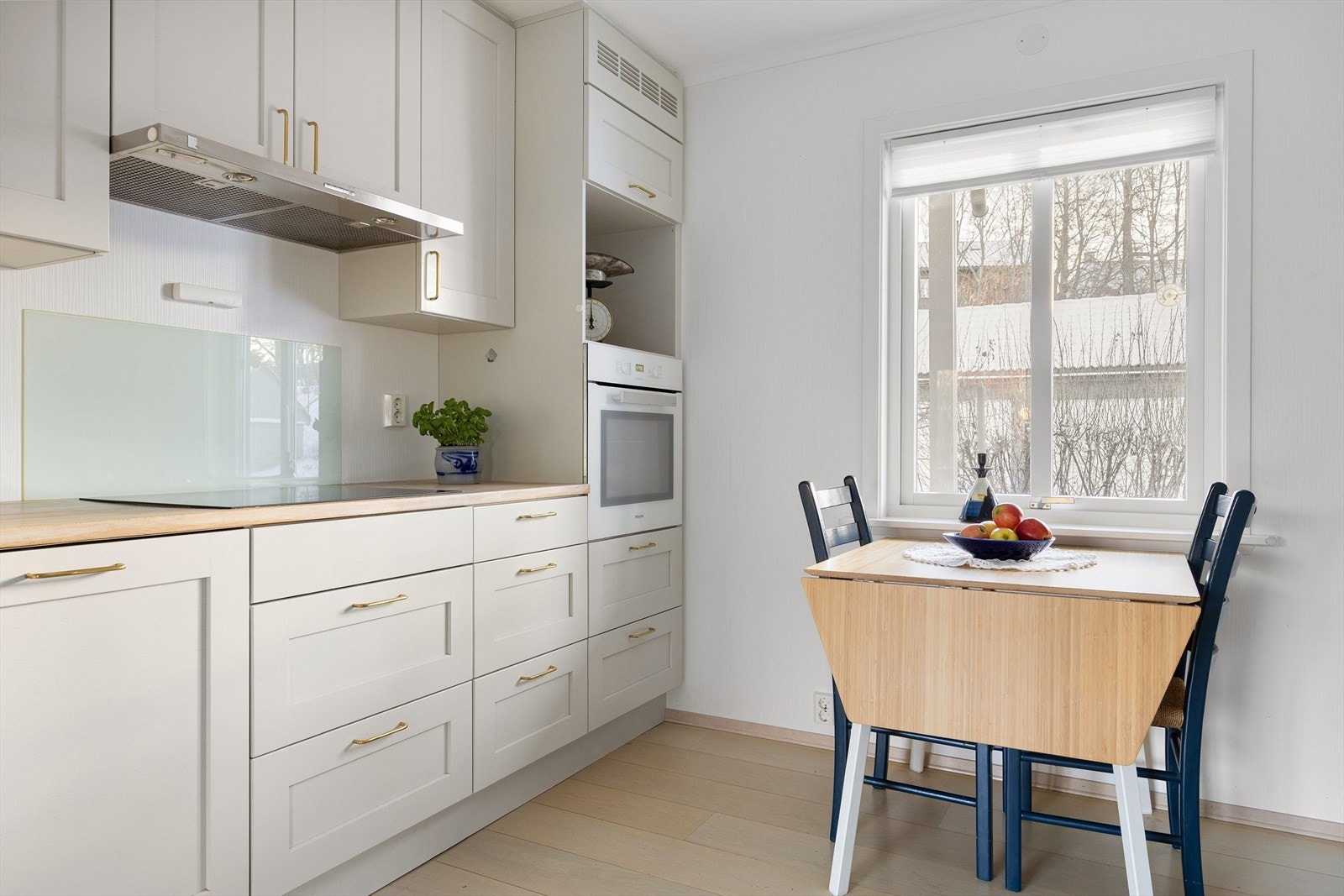 Pent kjøkken fra 2017 med hvite profilerte fronter (fra Huseby kjøkken), benkeplate av tre, innfelt vaskekum, og delvis integrerte hvitevarer fra Miele. Kjøkkenventilator fra Røroshetta. Galleribilde