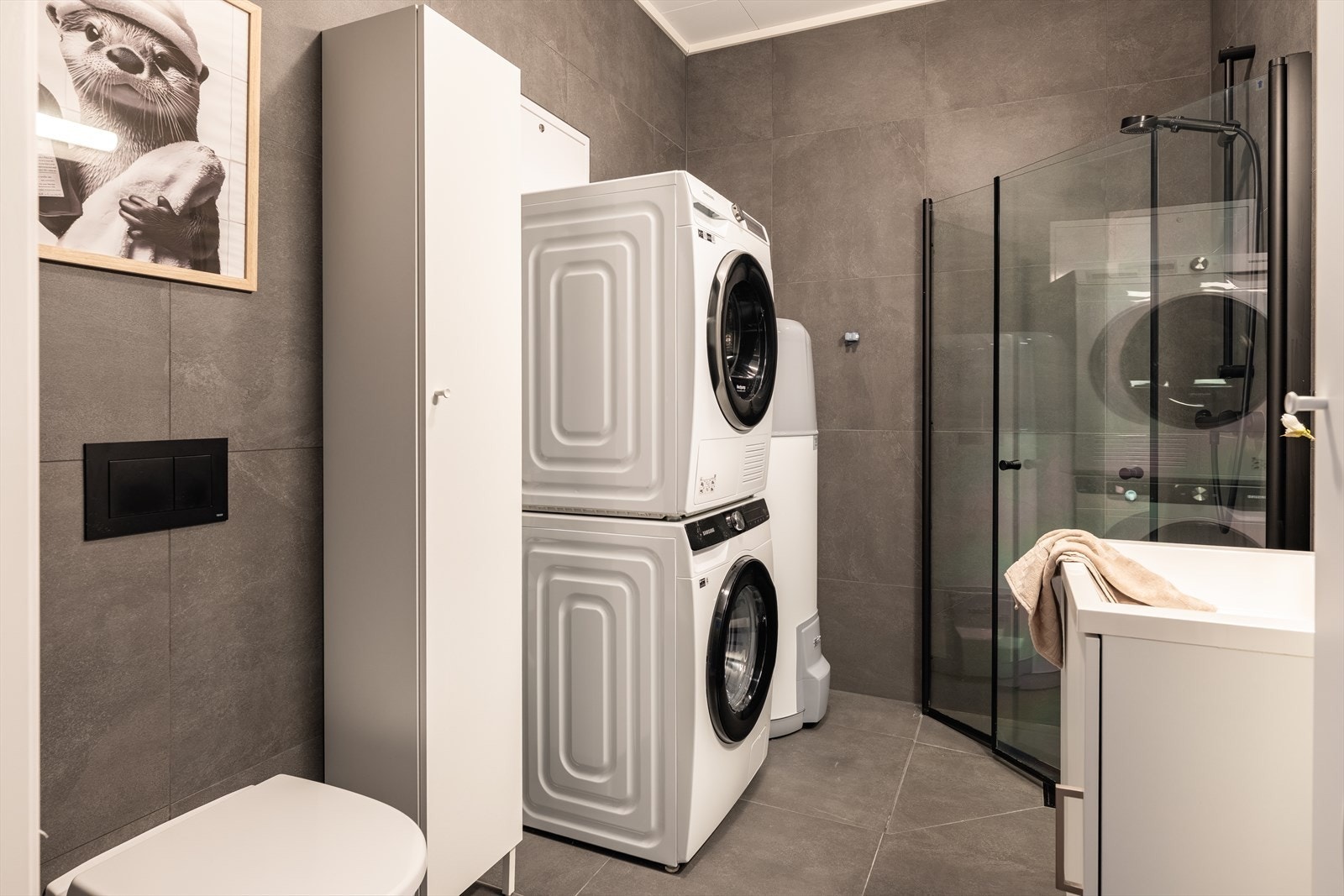 Baderom med vegghengt toalett og innredning med servant. Opplegg for vaskemaskin. Galleribilde