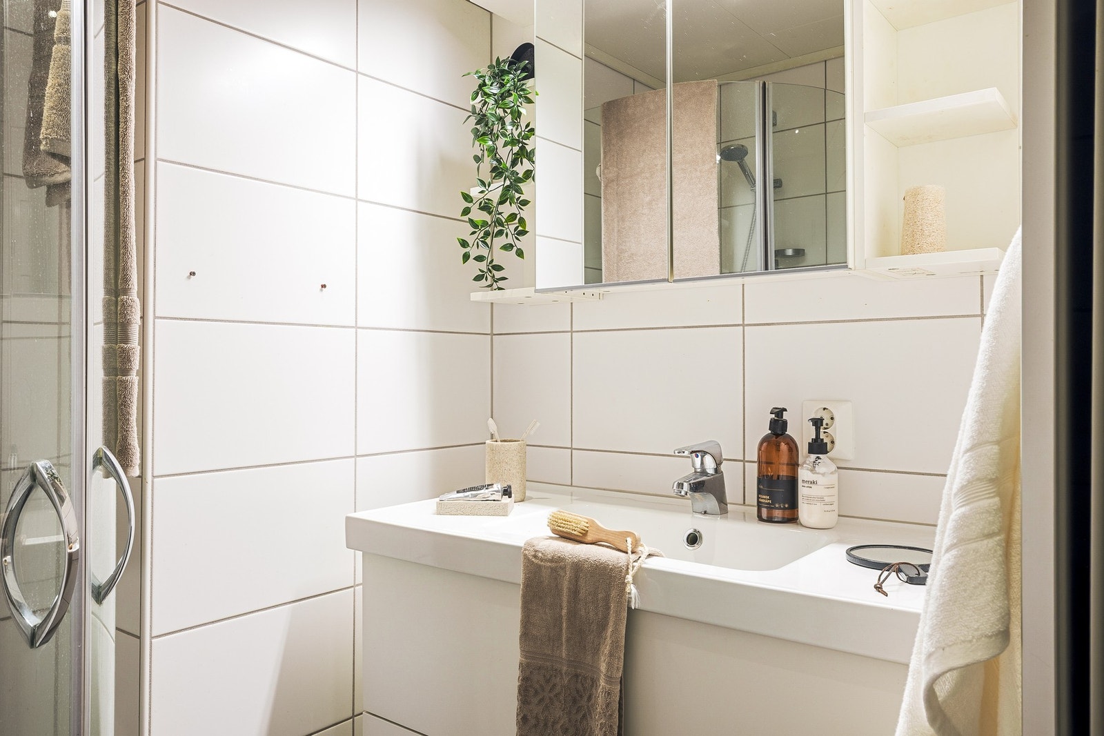 Badet er innredet med baderomsinnredning med nedfelt servant, vegghengt toalett, dusjhjørne og opplegg for vaskemaskin. Galleribilde