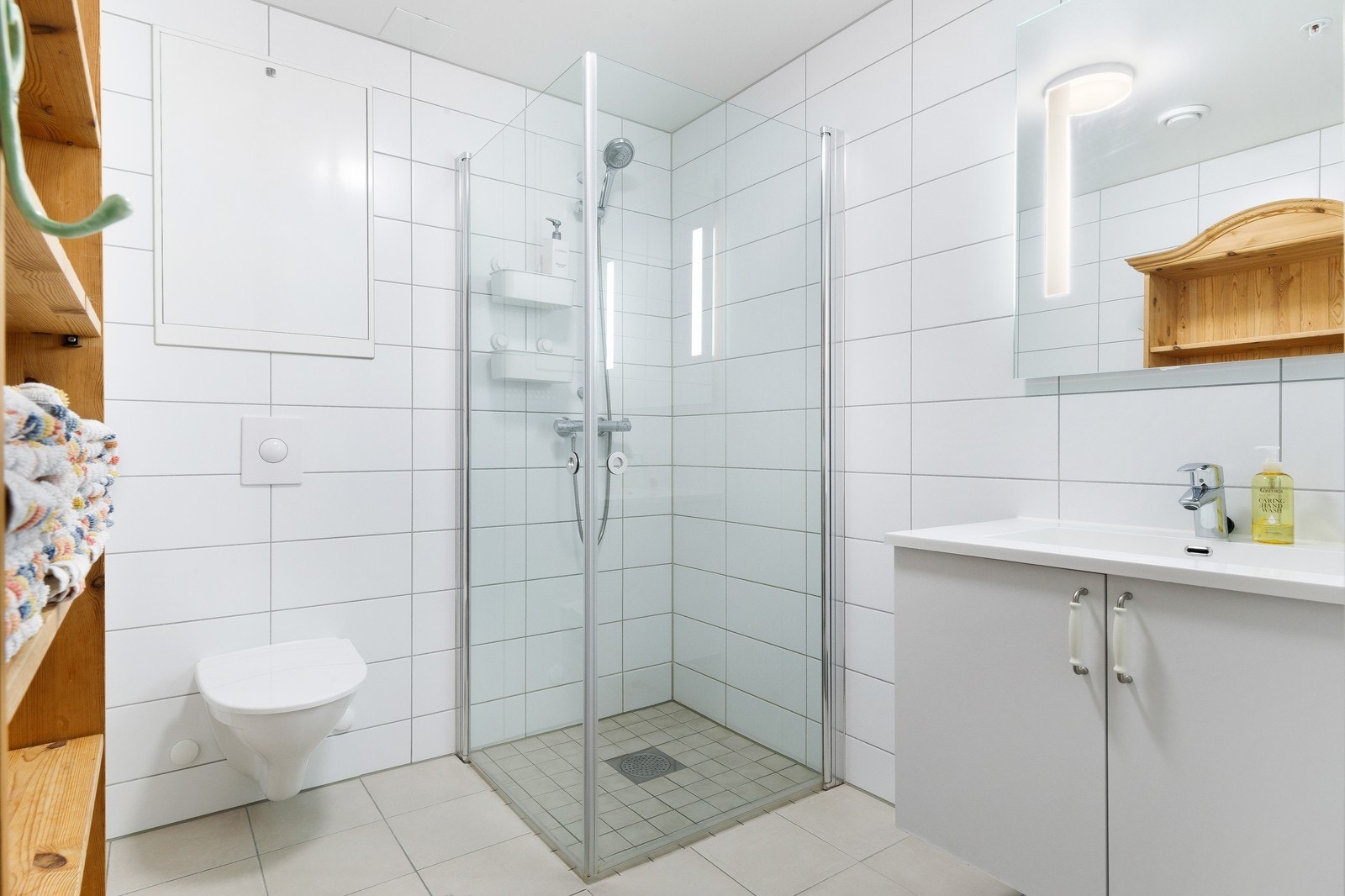 Helfliset baderom med dusjhjørne, baderomsmøbel med servant og toalett. Galleribilde