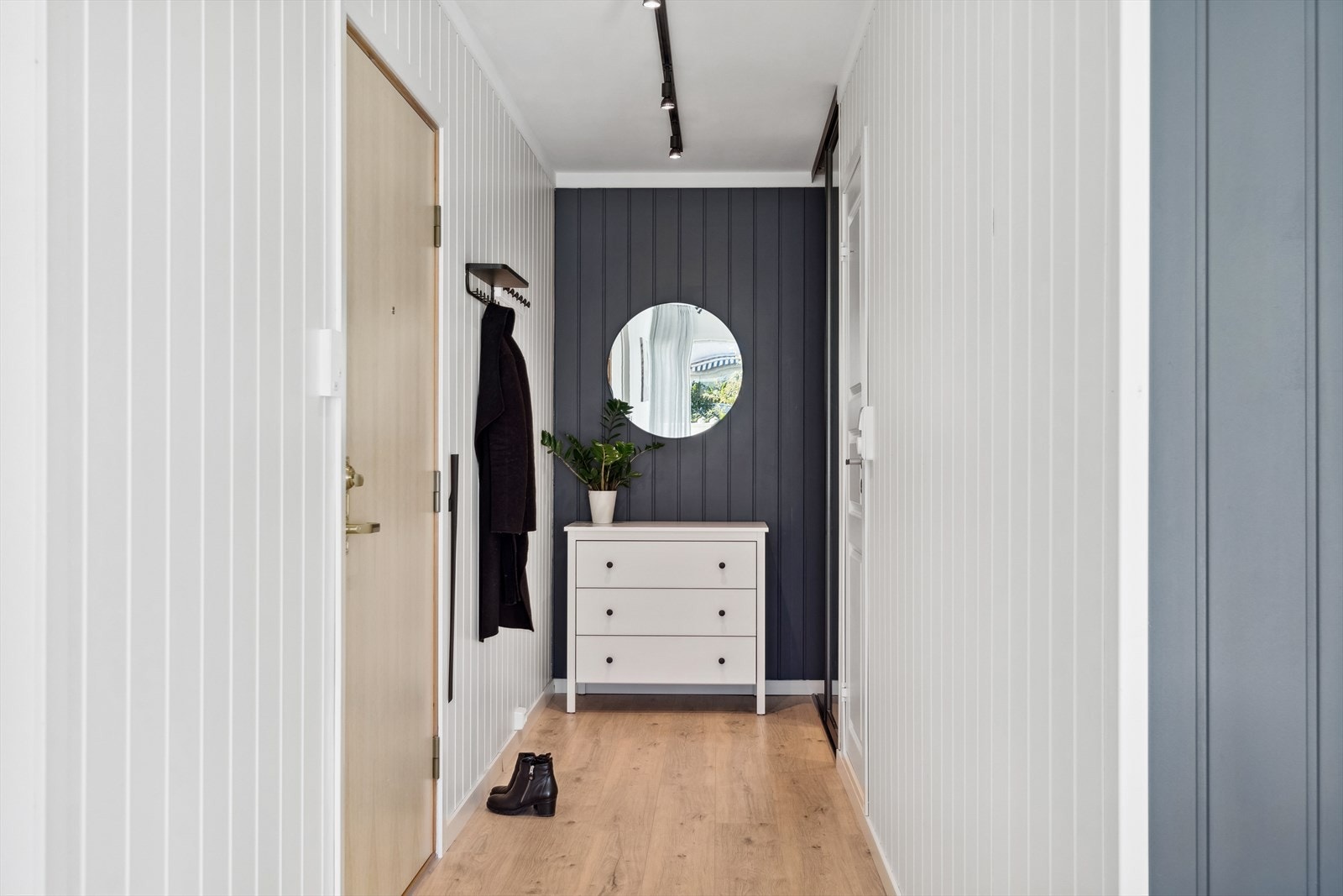 Den romslige entreen måler ca 6,5 m². Innerst i entreen er det montert en praktisk skyvedørsgarderobe fra Elfa (2022) med god plass til yttertøy og sko. Galleribilde