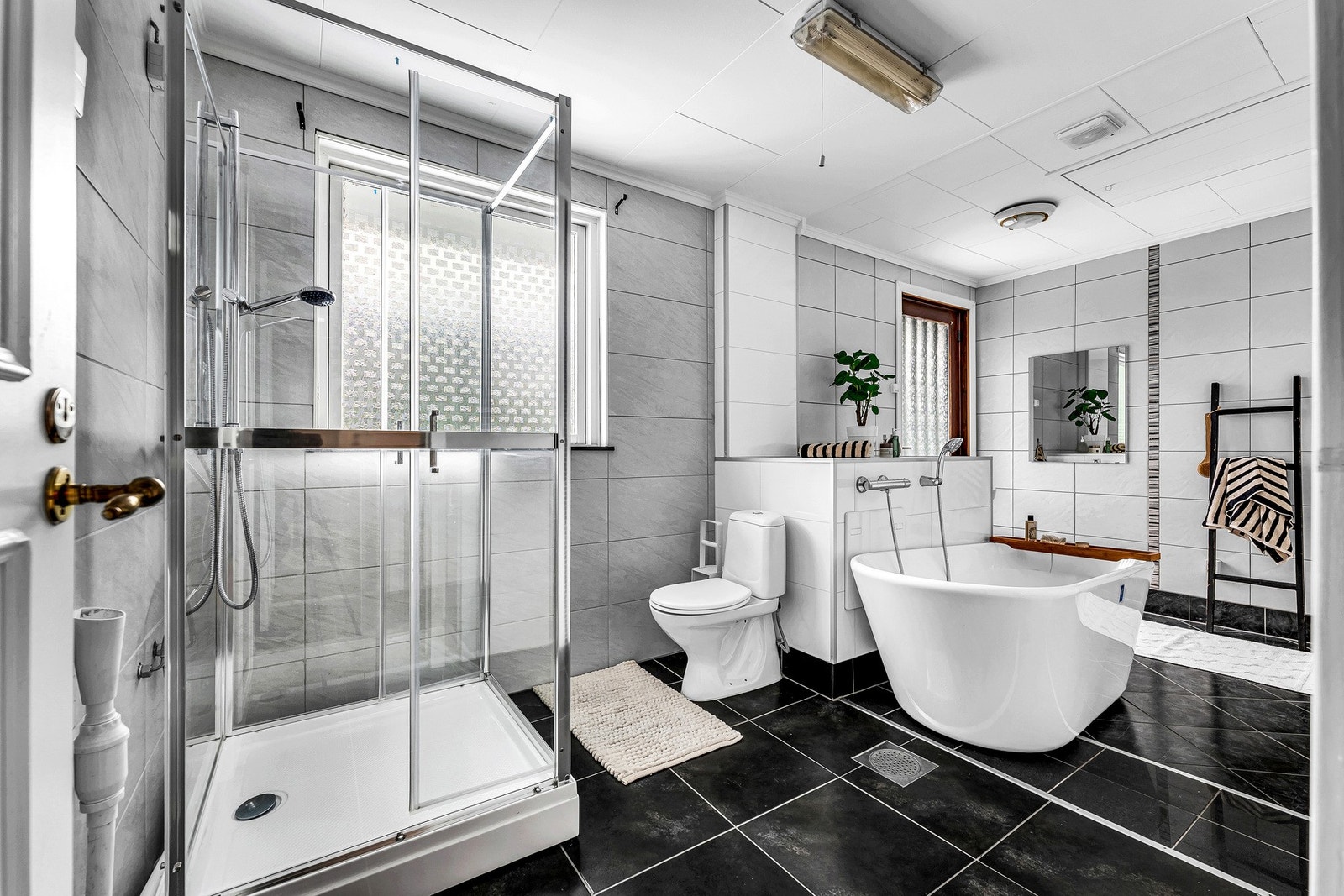 Stort baderom med dusjkabinett og opplegg for vaskemaskin Galleribilde