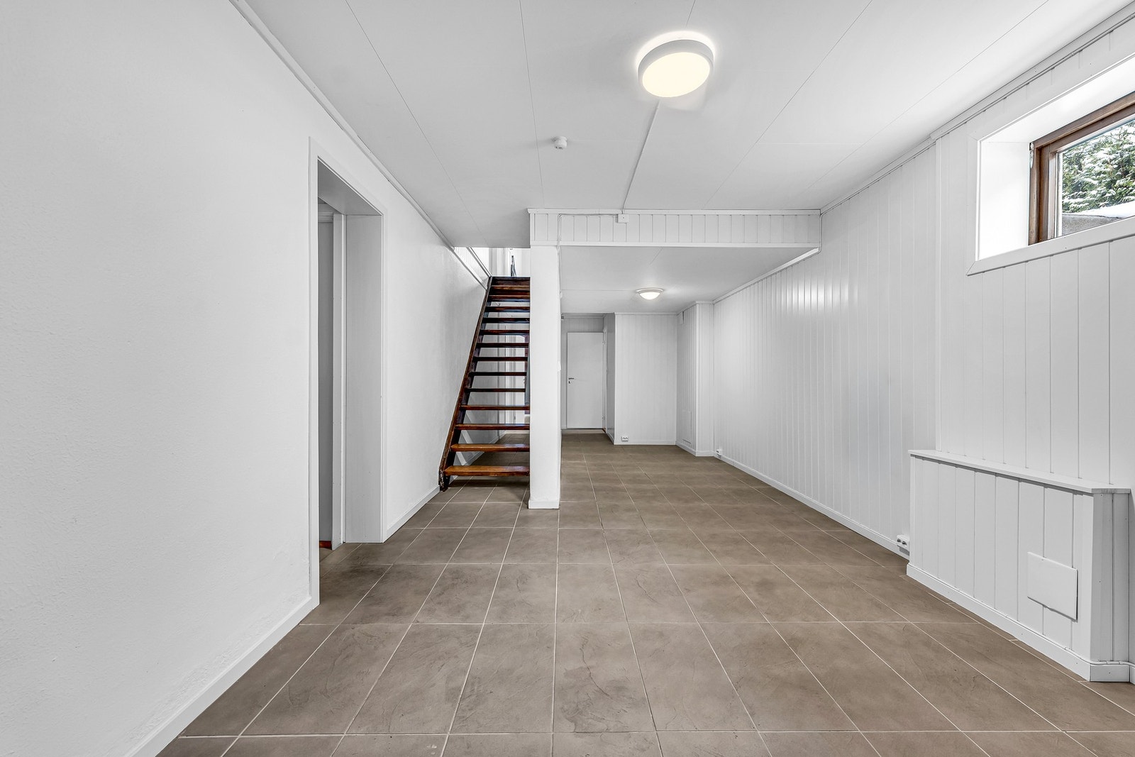 Stor og romslig hall i kjelleren med tilgang til alle rom samt ekstra trapp opp til 1.etasje. Galleribilde