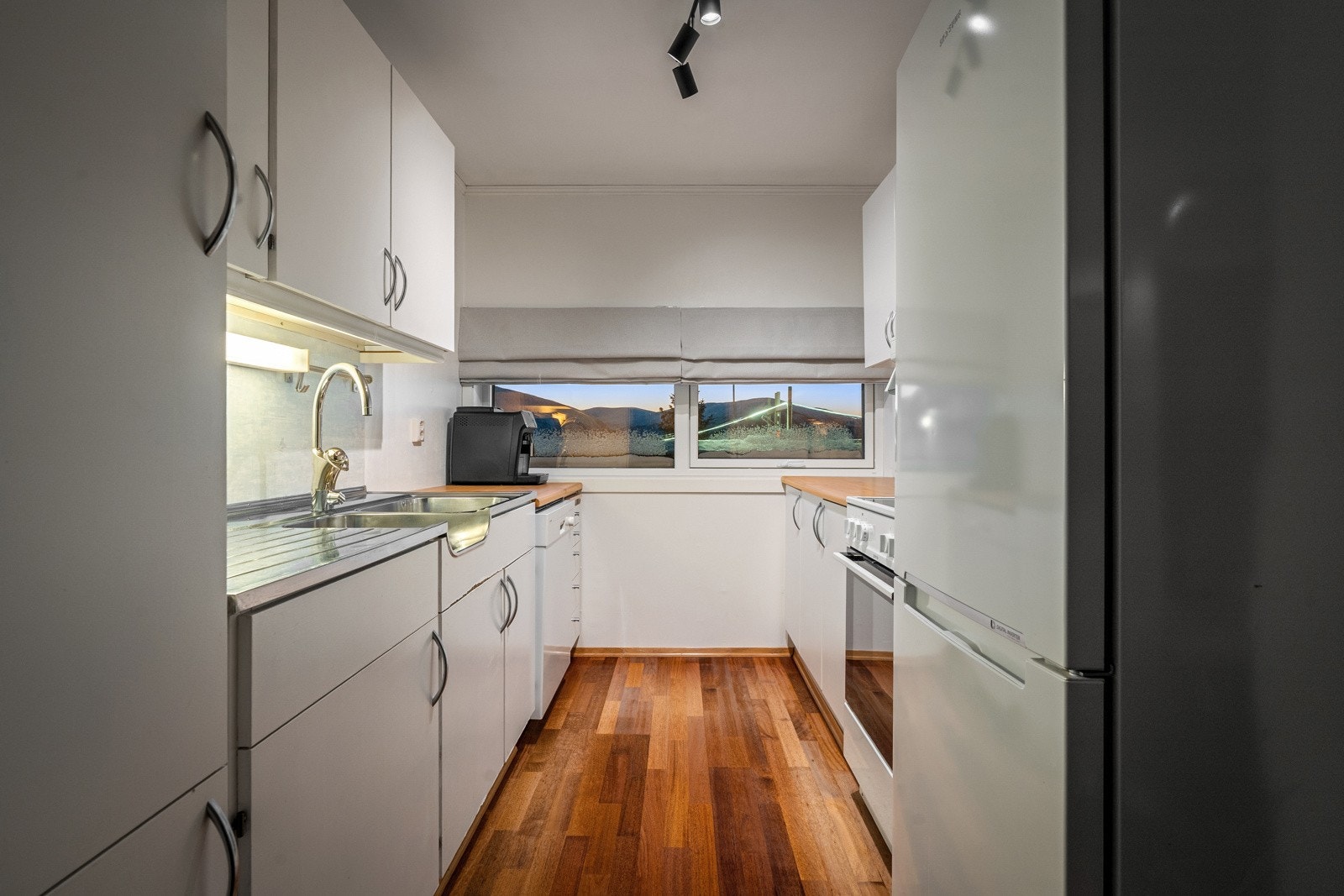 Kjøkken med slette fronter utstyrt med frittstående kjøl/fryseskap, oppvaskmaskin og ovn.