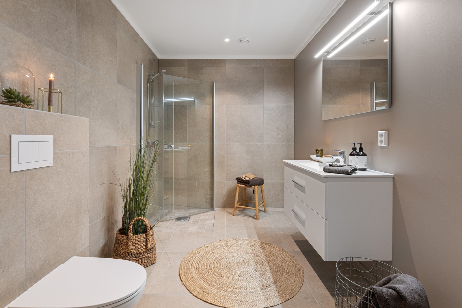 Lekkert bad med innredning med servant, vegghengt toalett og dusjvegger i glass. Galleribilde