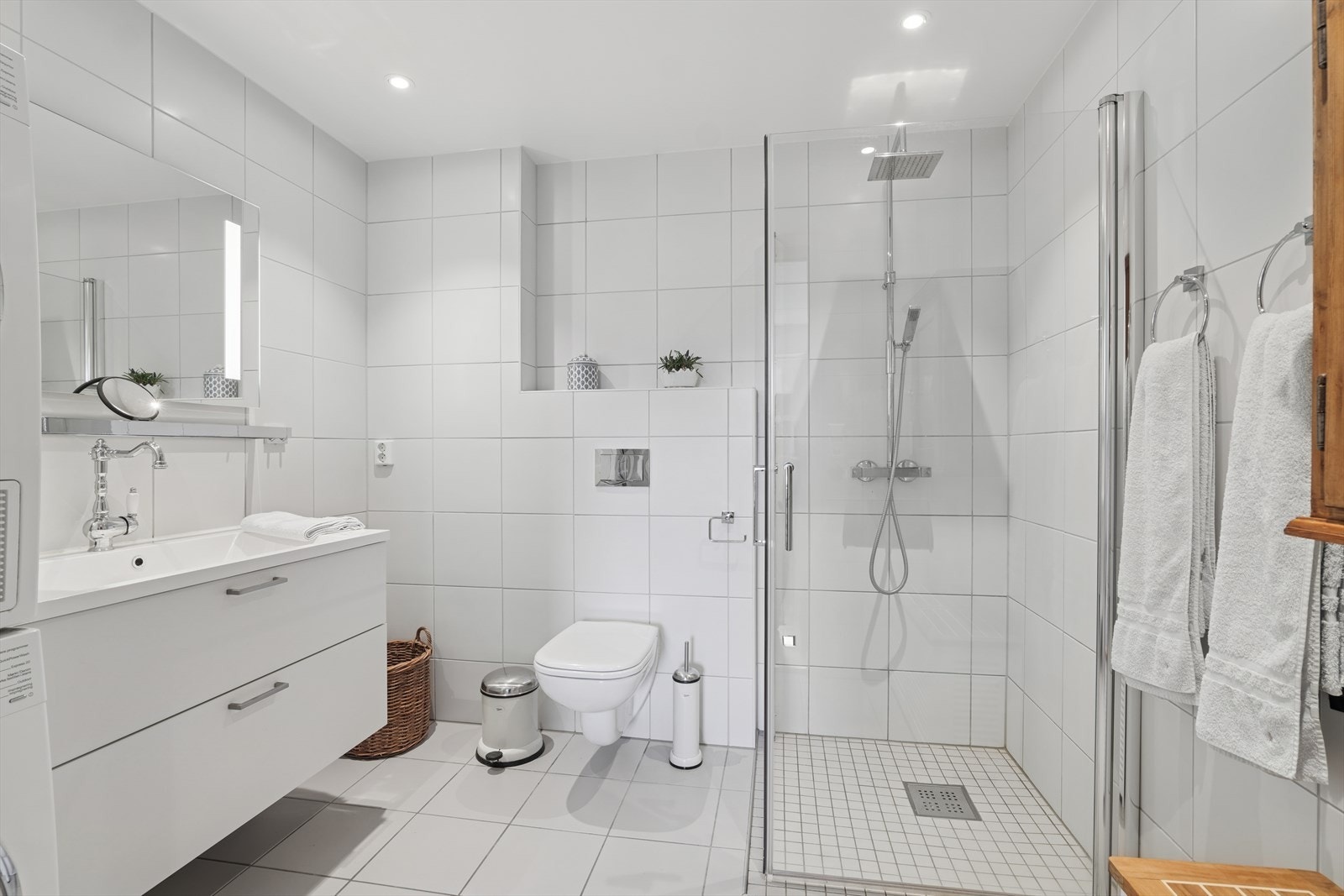 Badet er utstyrt med innredning med servant, speil med belysning, vegghengt wc, dusj med vegger og opplegg for vaskemaskin, noe som gjør det praktisk og brukervennlig. Galleribilde