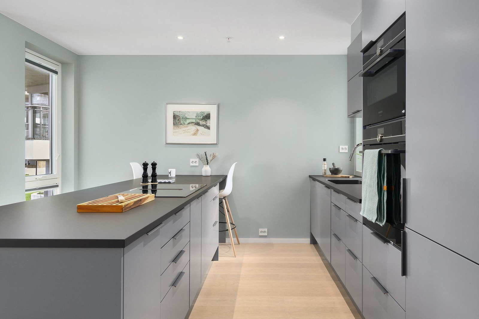 Kjøkkenøyen har oppbevaring på begge sider og er tillaget med barløsning inn mot veggen. Legg merke til at det er vindusåpning på begge sider av kjøkkenet! Foto: Diakrit (Krisztian Sere) Galleribilde