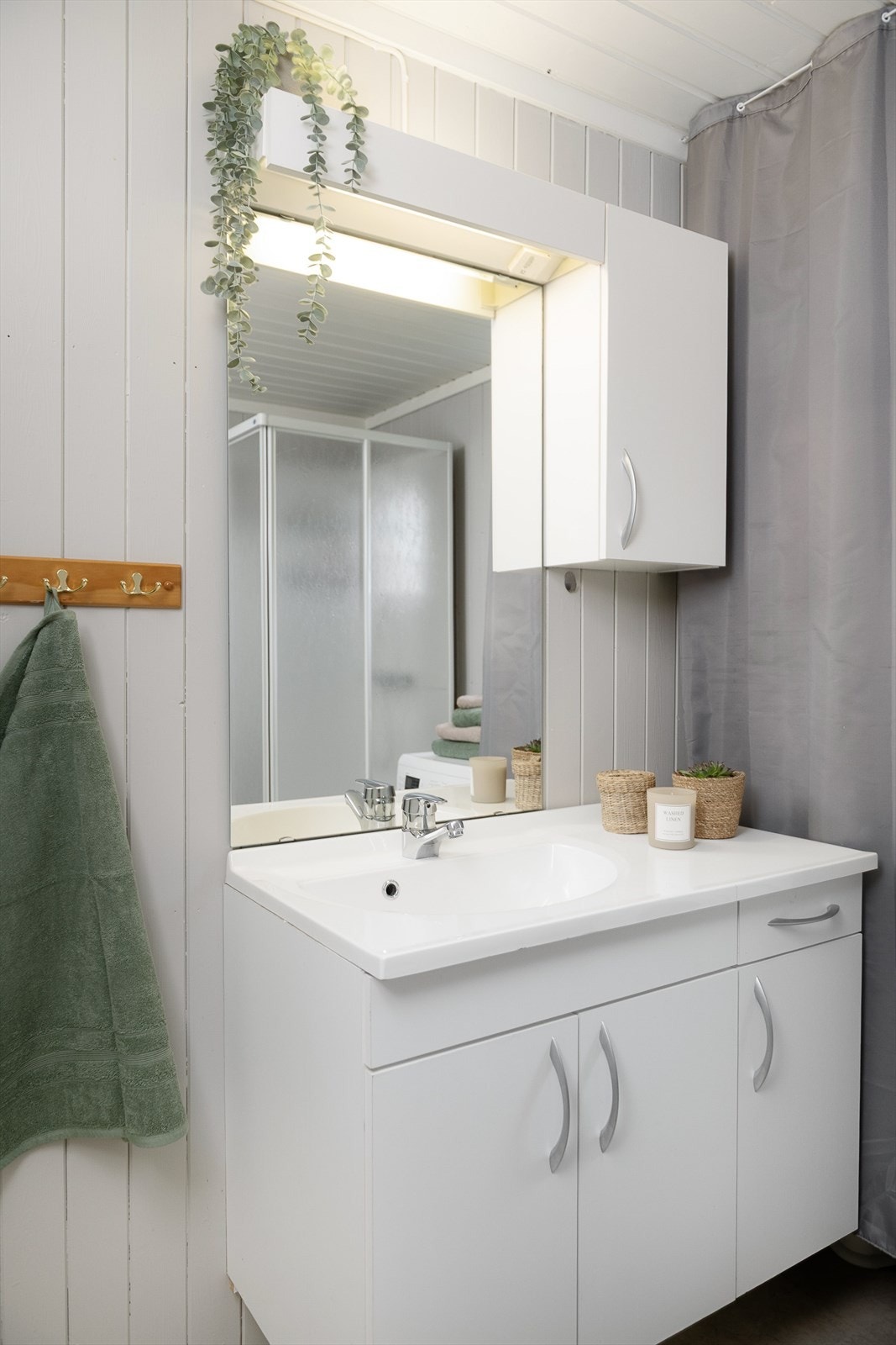 Baderomsinnredningen har glatte, hvite fronter. Skap for oppbevaring. Galleribilde