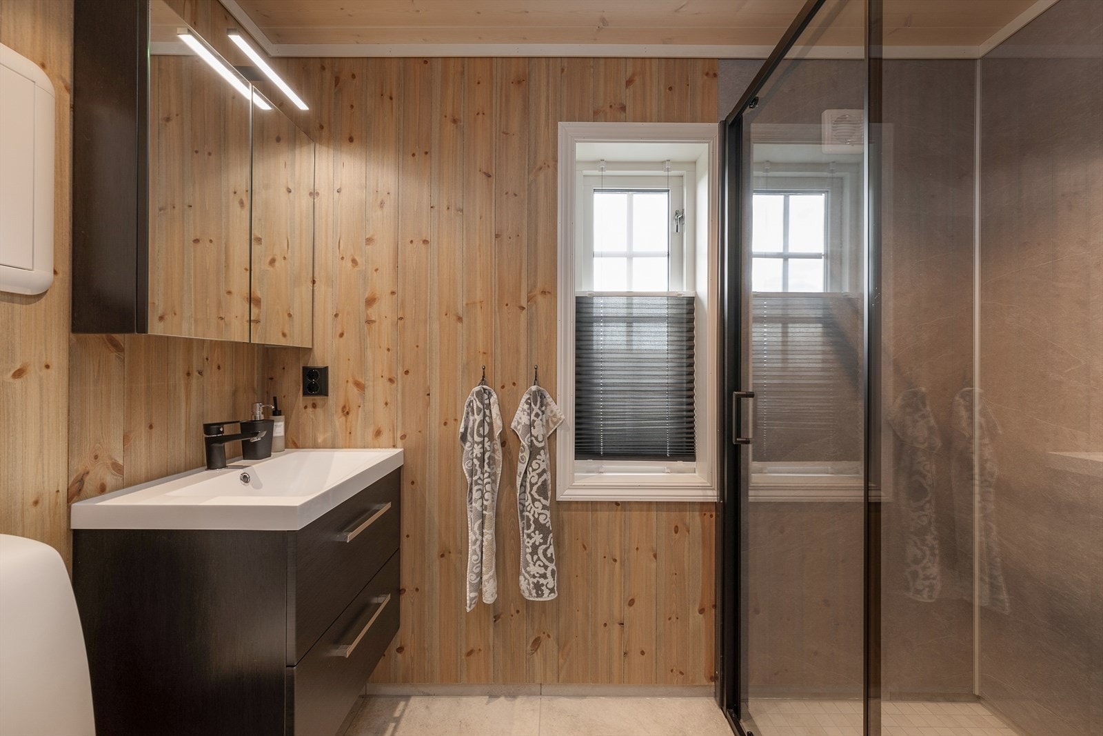 Pent og innbydende bad i annekset med dusj, wc og baderomsinnredning med skuffer for oppbevaring. Galleribilde