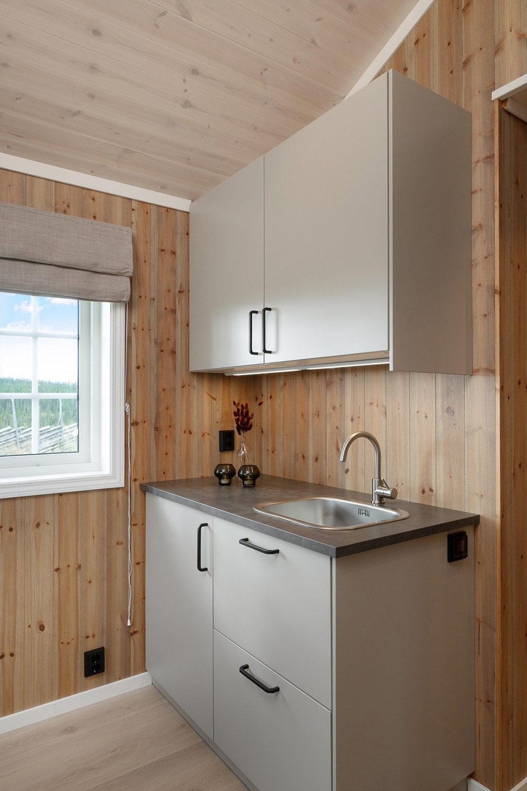 Kjøkkenet i annekset har skap og skuffer for oppbevaring. Glatte fronter i lun fargetone. Benkeplate i laminat utførelse. Galleribilde