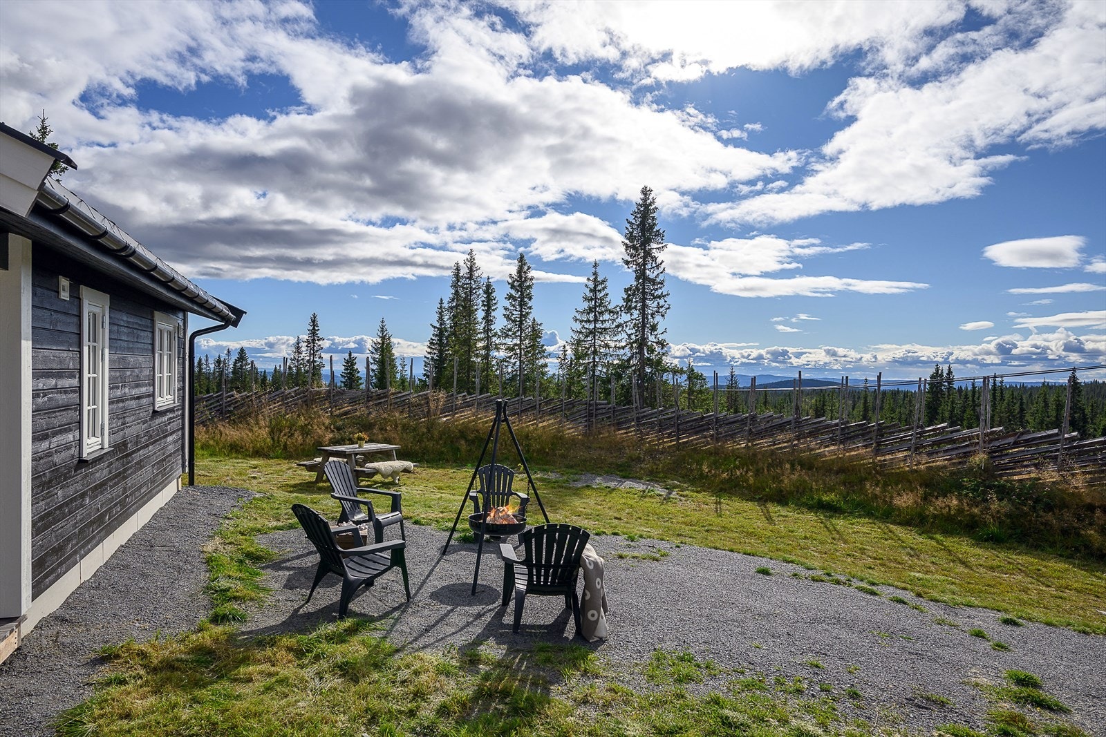 Utrolig hyggelig uteområde rundt hytta med en blanding av gruset adkomst og gressbakke/naturtomt. En skigard lager en fin ramme rundt deler av tomta. Galleribilde