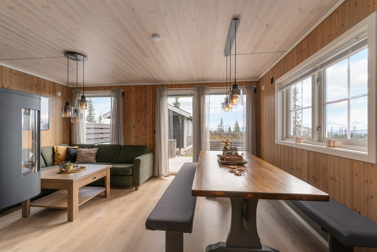Oppholdsrommet i hytta er lunt og hyggelig. Her er det plass til både langbord og sofa foran peisovnen. Galleribilde