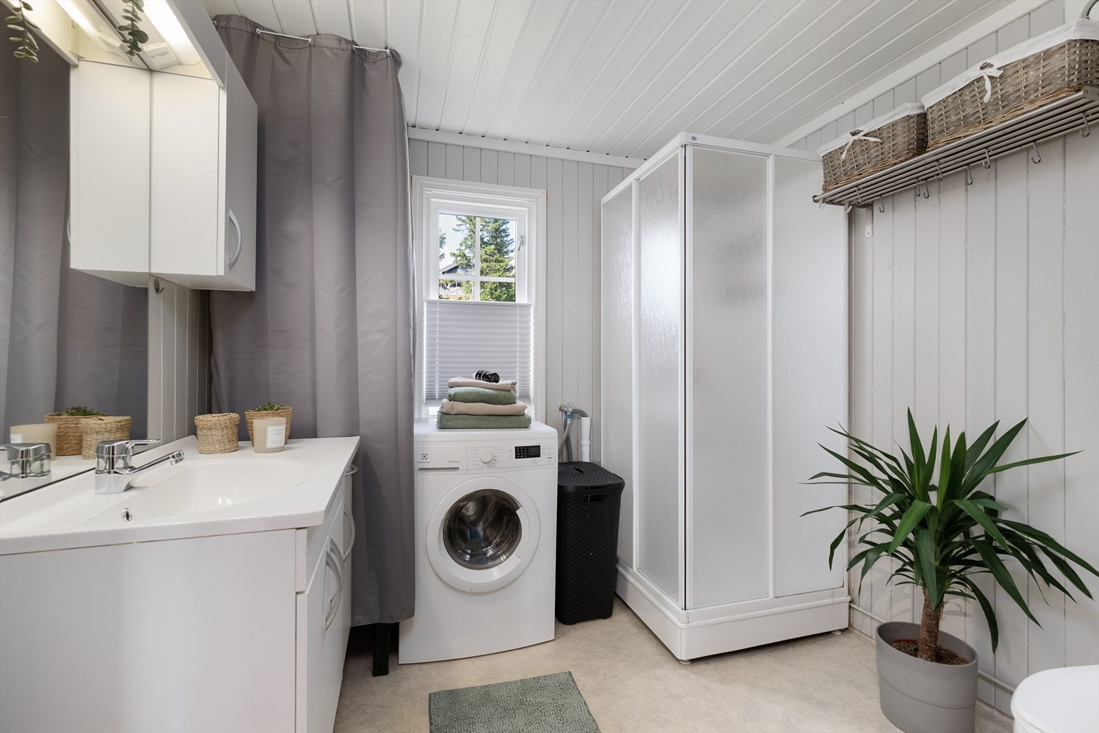 Funksjonelt bad/wc har dusjkabinett, WC, baderomsinnredning samt opplegg for vaskemaskin. Galleribilde