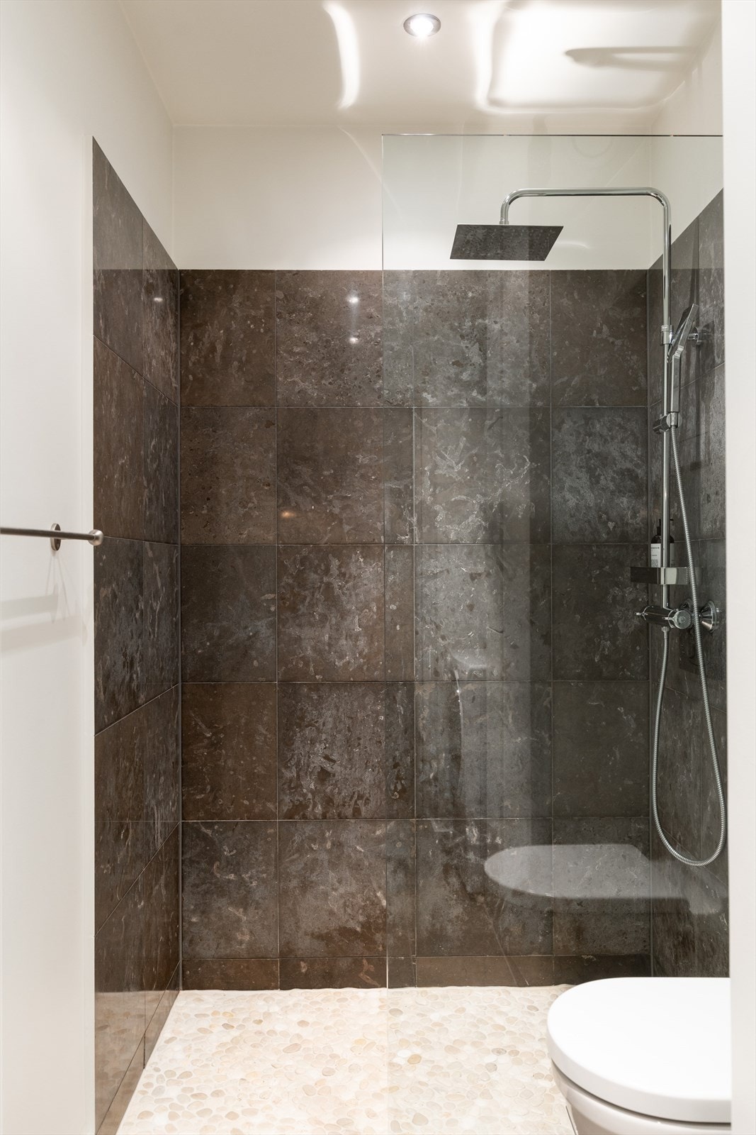 Badet er innredet med vegghengt klosett, servant og dusjhjørne med glassfelt. Galleribilde