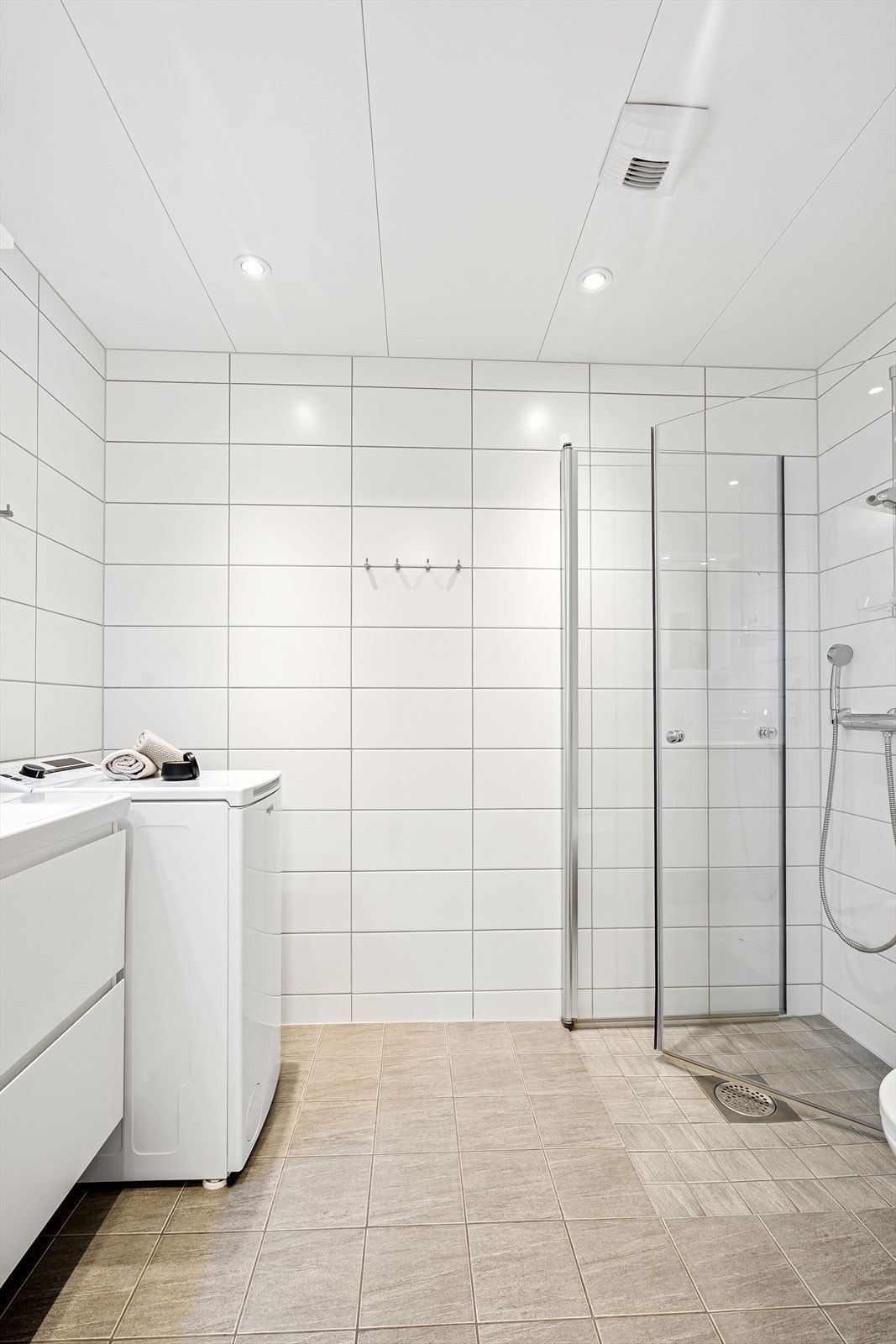 Her er det varmekabler i gulv, opplegg for mindre vaskemaskin samt servant i tilknytning speil, fritthengende toalett og hjørnedusj med glassdører. Galleribilde