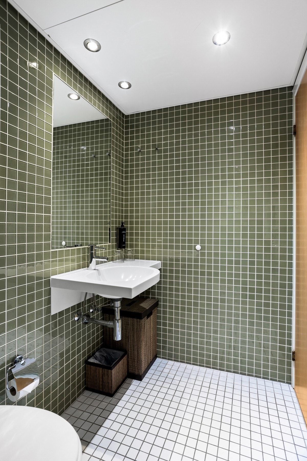 Hovedbadet har lyse fliser på gulv med behagelig gulvvarme, flislagte vegger, downlights i himling og praktiske veggnisjer for oppbevaring. Galleribilde