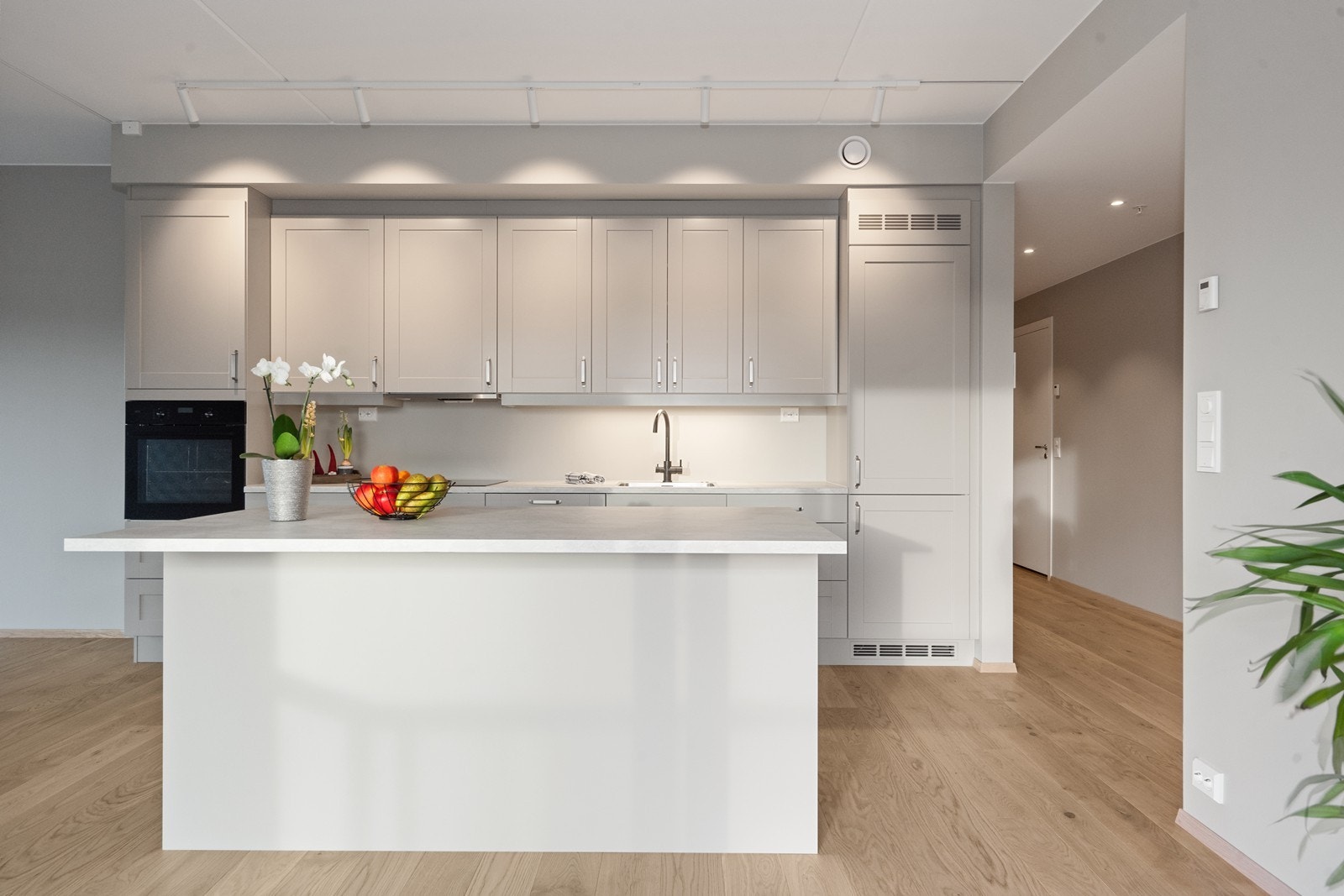 Kjøkkenet har profilerte fronter i varm gråtone og benkeplate i laminat med nedfelt kum. Galleribilde