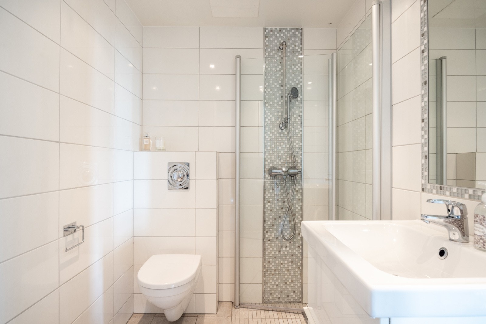 Baderom med moderne uttrykk, flislagte vegger og gulv med elektriske varmekabler. Galleribilde