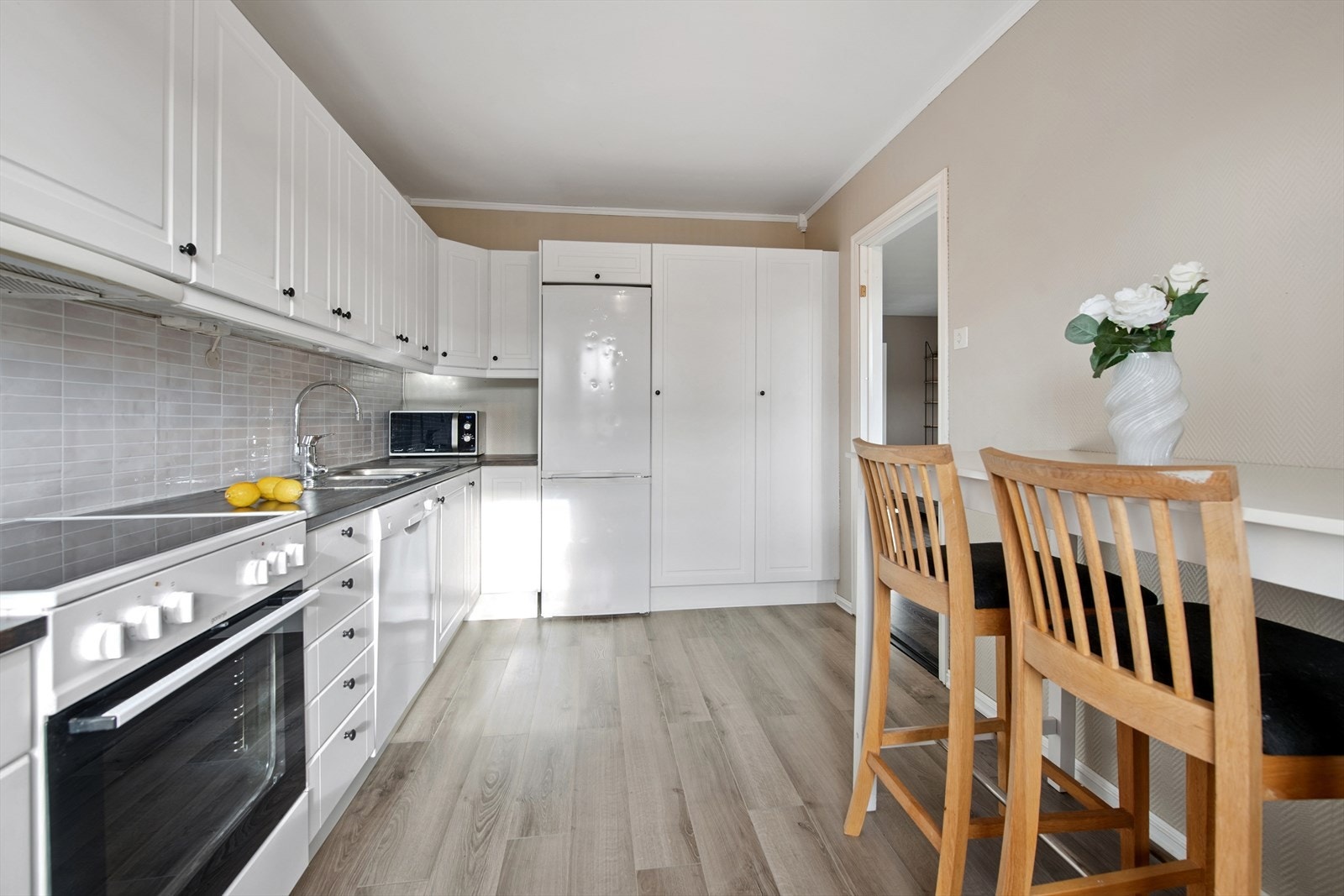 Meget pent kjøkken med godt med skapplass, lakkert heltre bennkeplate og 3D folie mellom benk og overskap - frittstående hvitevarer. Galleribilde