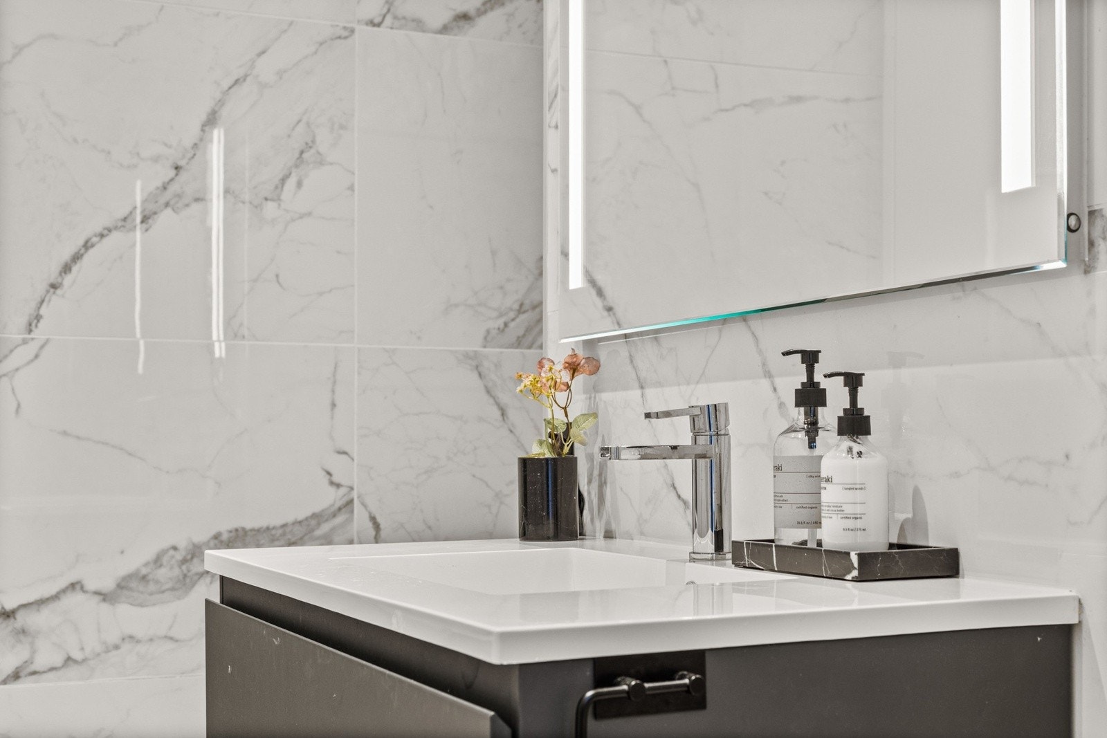 Servant med stilren innredning, speil med belysning og veggmontert toalett gir et helhetlig og elegant uttrykk. Galleribilde