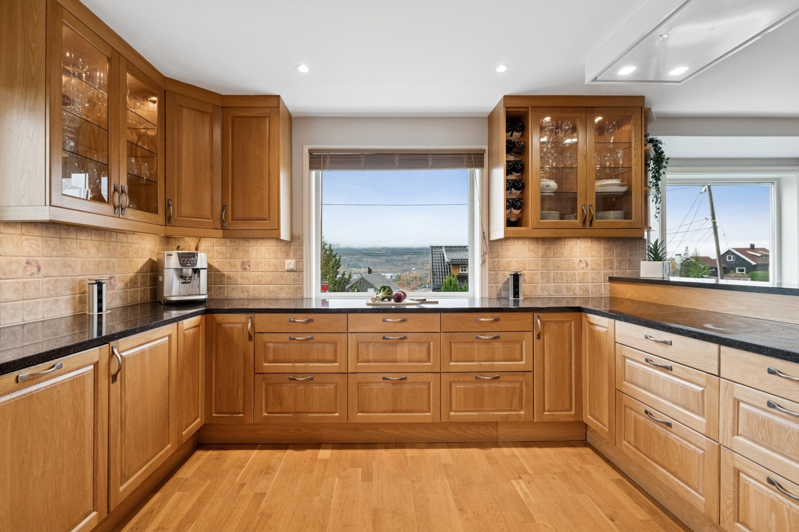 Tidløst kjøkken med heltre innredning, steinbenk og vakker utsikt. Galleribilde