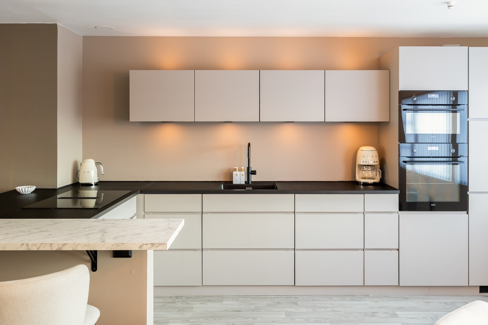 Moderne og grepsfritt hjørnekjøkken med kjøkkenøy fra Kvik med slette fronter og tidløst design. Galleribilde