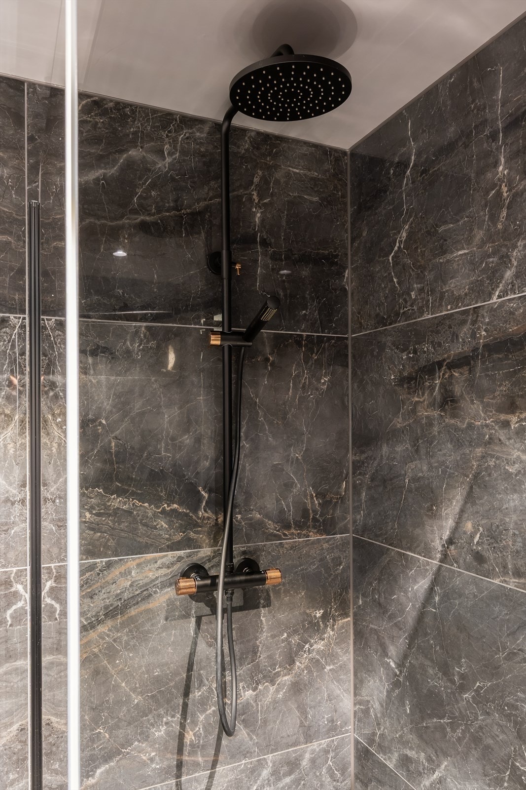 Badet har kvaliteter som blant annet regnfallsdusj, vegghengt toalett i sort, dusjdør i sort sotet, speil med lys og gulvvarme. Galleribilde