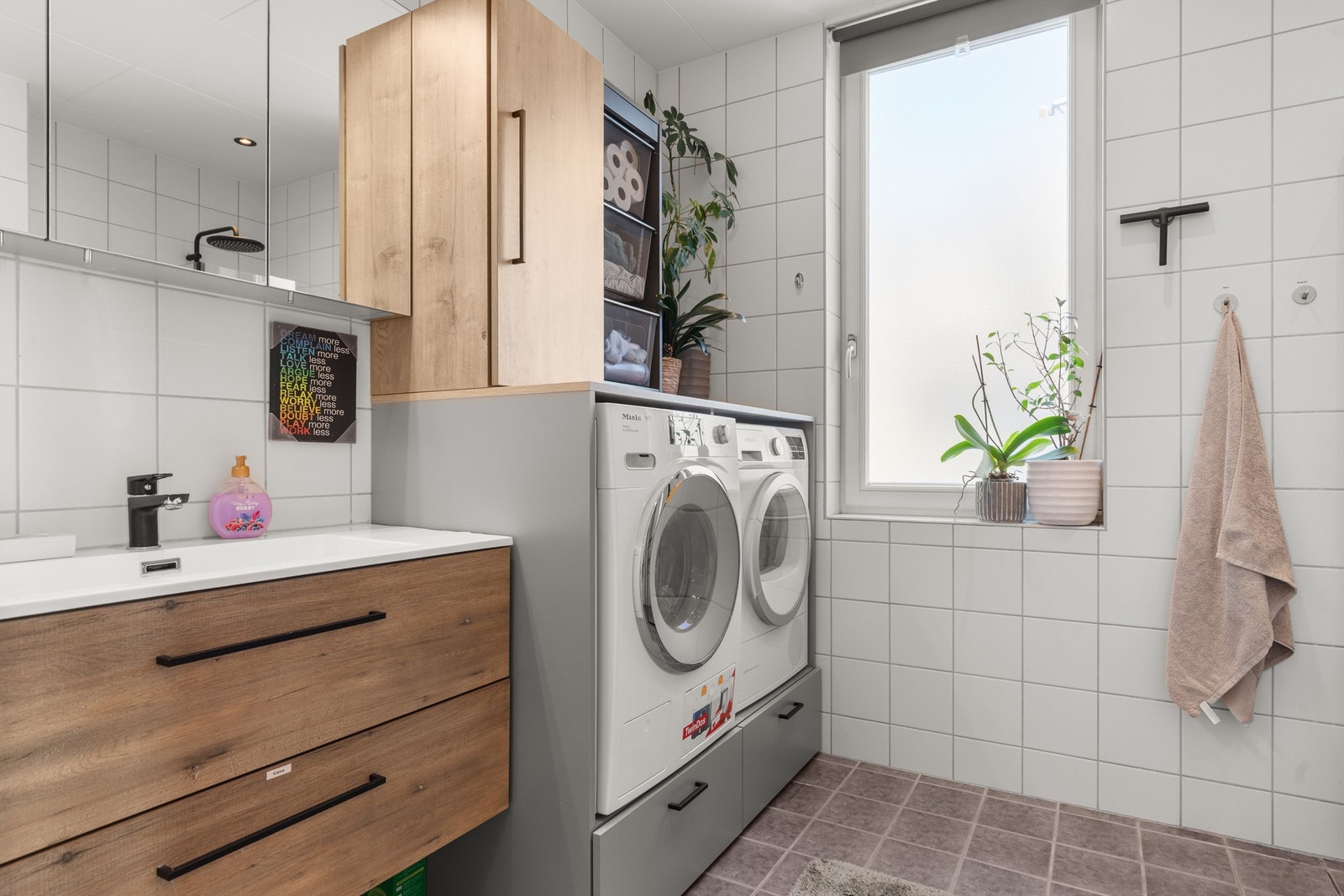 Badet er innredet med vegghengt klosett, servant med innredning, speilskap m/lys og dusjhjørne med svingbare glassdører. Det er både plass og opplegg for vaskemaskin og tørketrommel i nisje innredning. Galleribilde